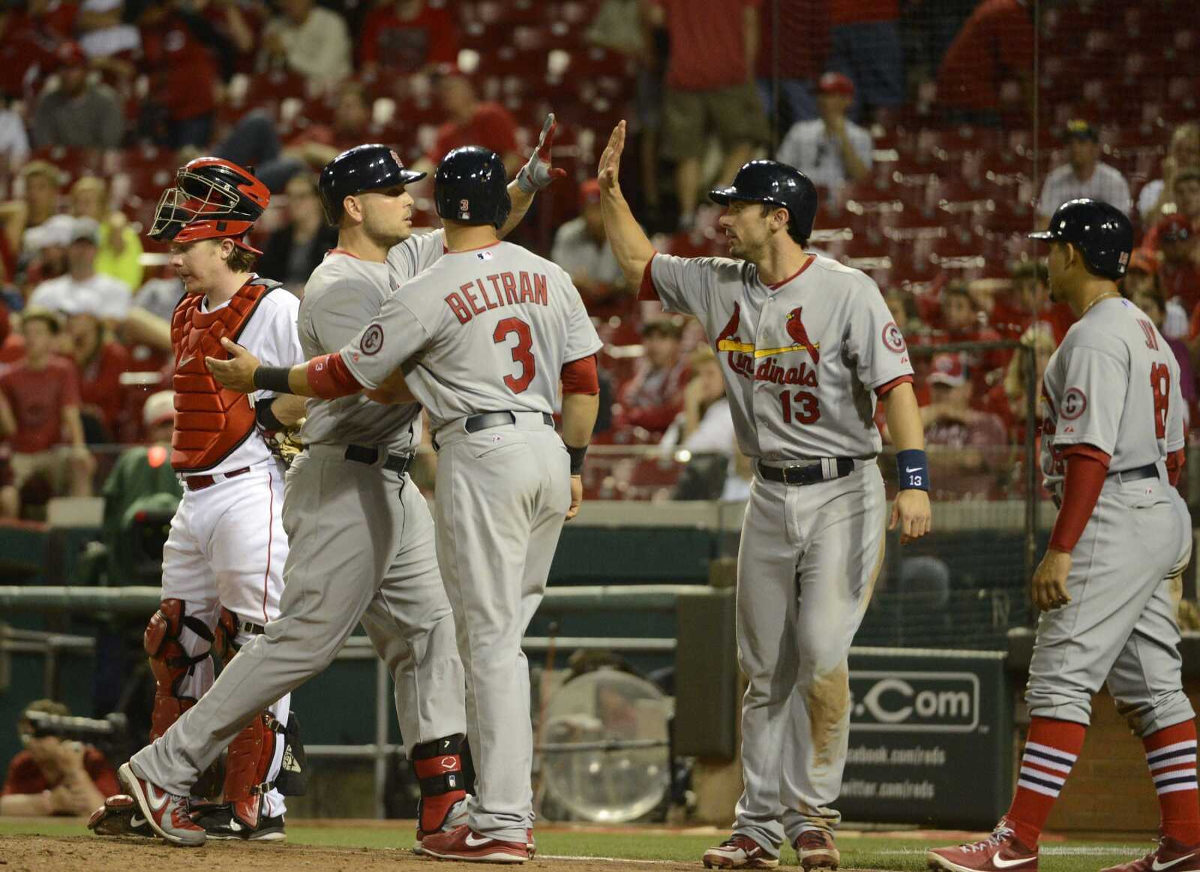 Matt Holliday, second from left, is congratulated at home plate after his 10th inning grand slam in a game where the St. Louis Cardinals beat the Cincinnati Reds 11-4 in 10 innings, Sunday, June 9, 2013, at Great American Ball Park in Cincinnati. (AP Photo/ Michael E. Keating)