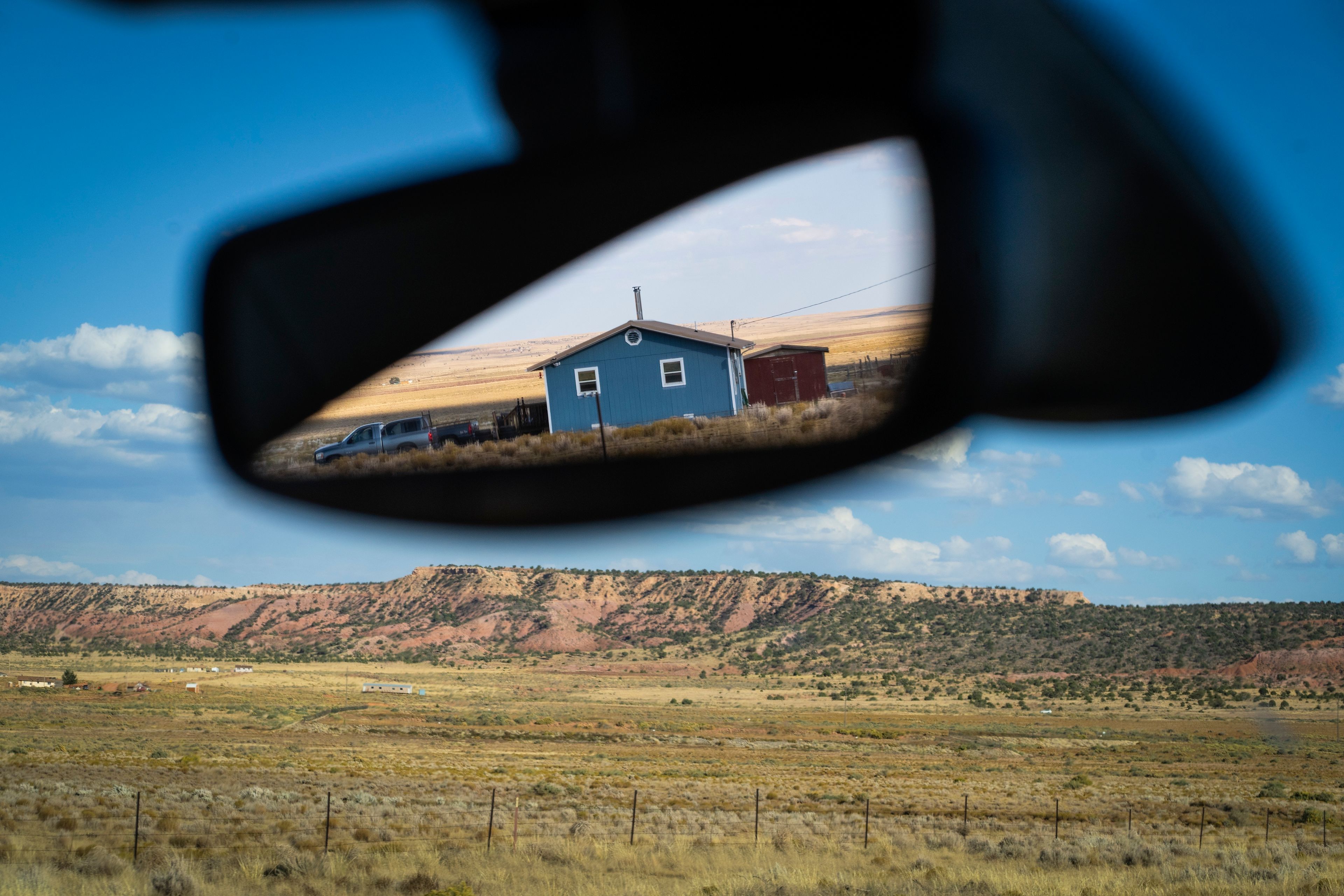 A house is reflected in a car's rearview mirror, on the Navajo Nation, on the outskirts of Window Rock, Ariz., Friday, Oct. 11, 2024. (AP Photo/Rodrigo Abd)