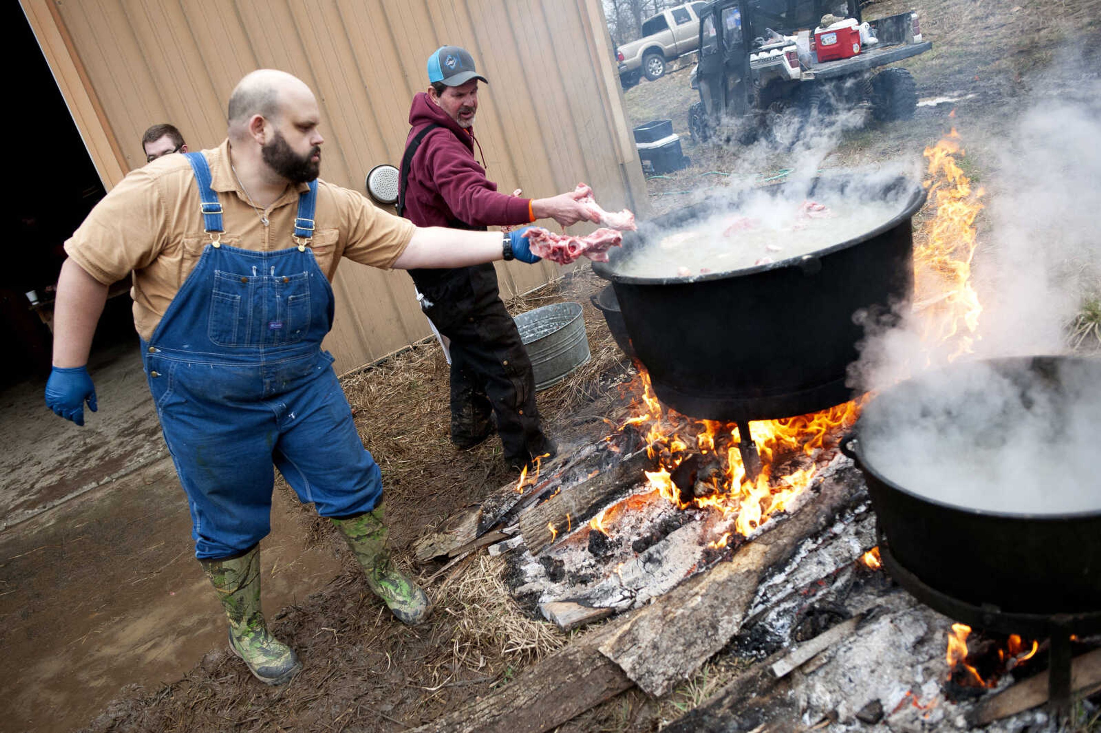 Andy Kliefoth of Kansas City, Missouri, (left) and Pat Hotop put hog parts into a pot to cook. Diane Mahnken of Perryville, one of Rueben Hotop's 13 children, said normally they take the cooked meat and, using the hog blood, make blood sausage, but this year the blood wasn't kept like it was supposed to be. This year Mahnken said they'll use the cooked meat to make either head cheese, liver sausage or something of that nature. Published March 2.