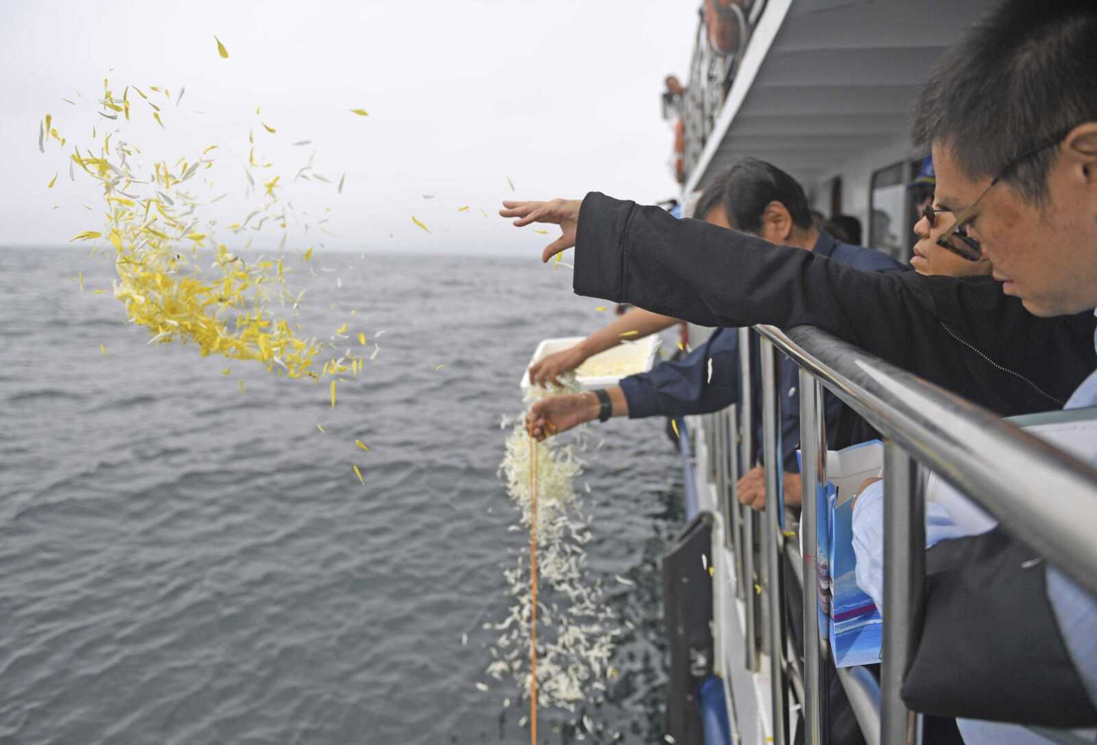 Liu Xia, in black, wife of imprisoned Chinese Nobel Peace Prize laureate Liu Xiaobo, throws flower petals as Liu's ashes are buried at sea Saturday off the coast of Dalian in northeastern China's Liaoning province.