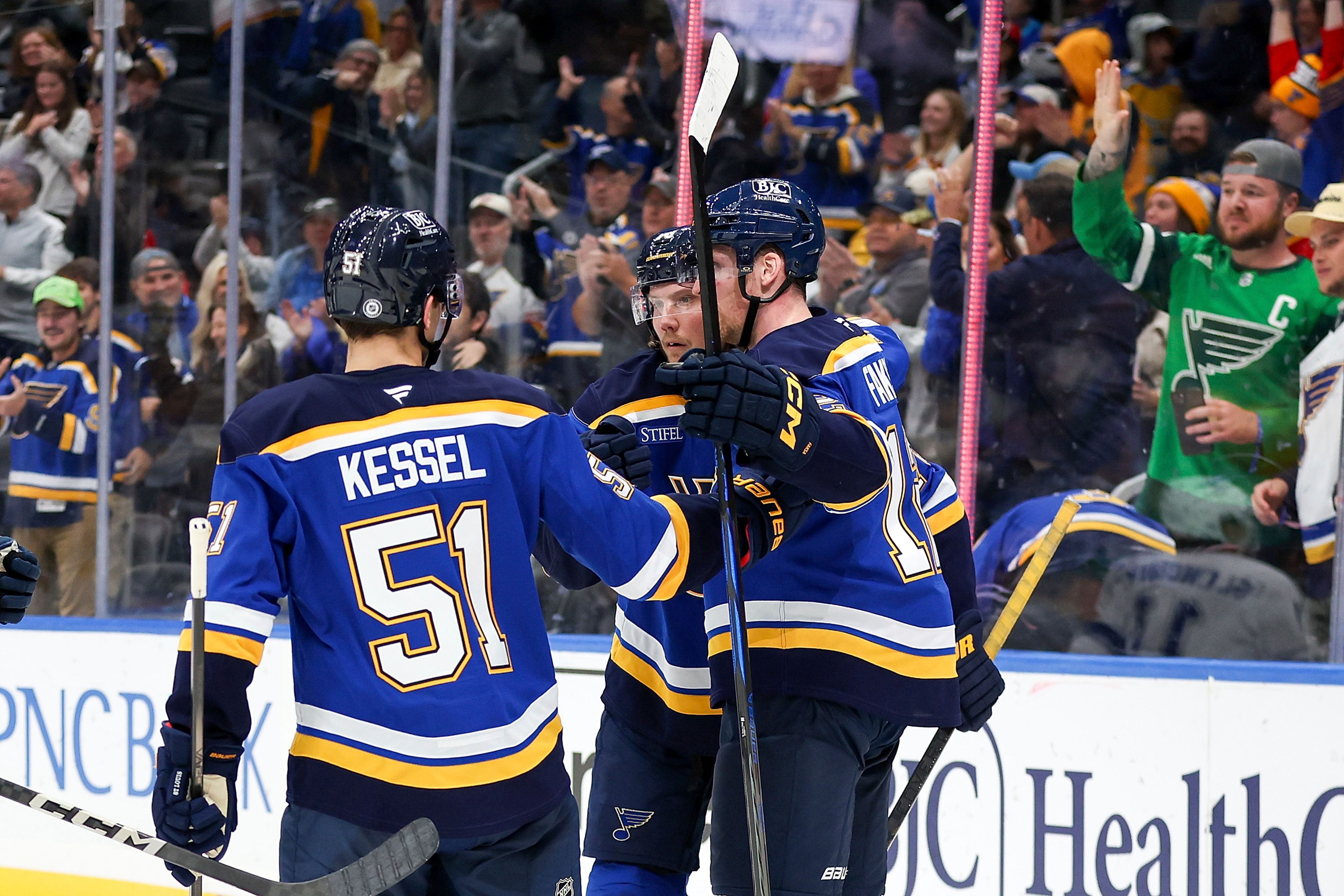 St. Louis Blues' Oskar Sundqvist, center, is congratulated by teammates Matthew Kessel (51) and Radek Faksa (12) after scoring a goal during the second period of an NHL hockey game against the Tampa Bay Lightning Tuesday, Nov. 5, 2024, in St. Louis. (AP Photo/Scott Kane)