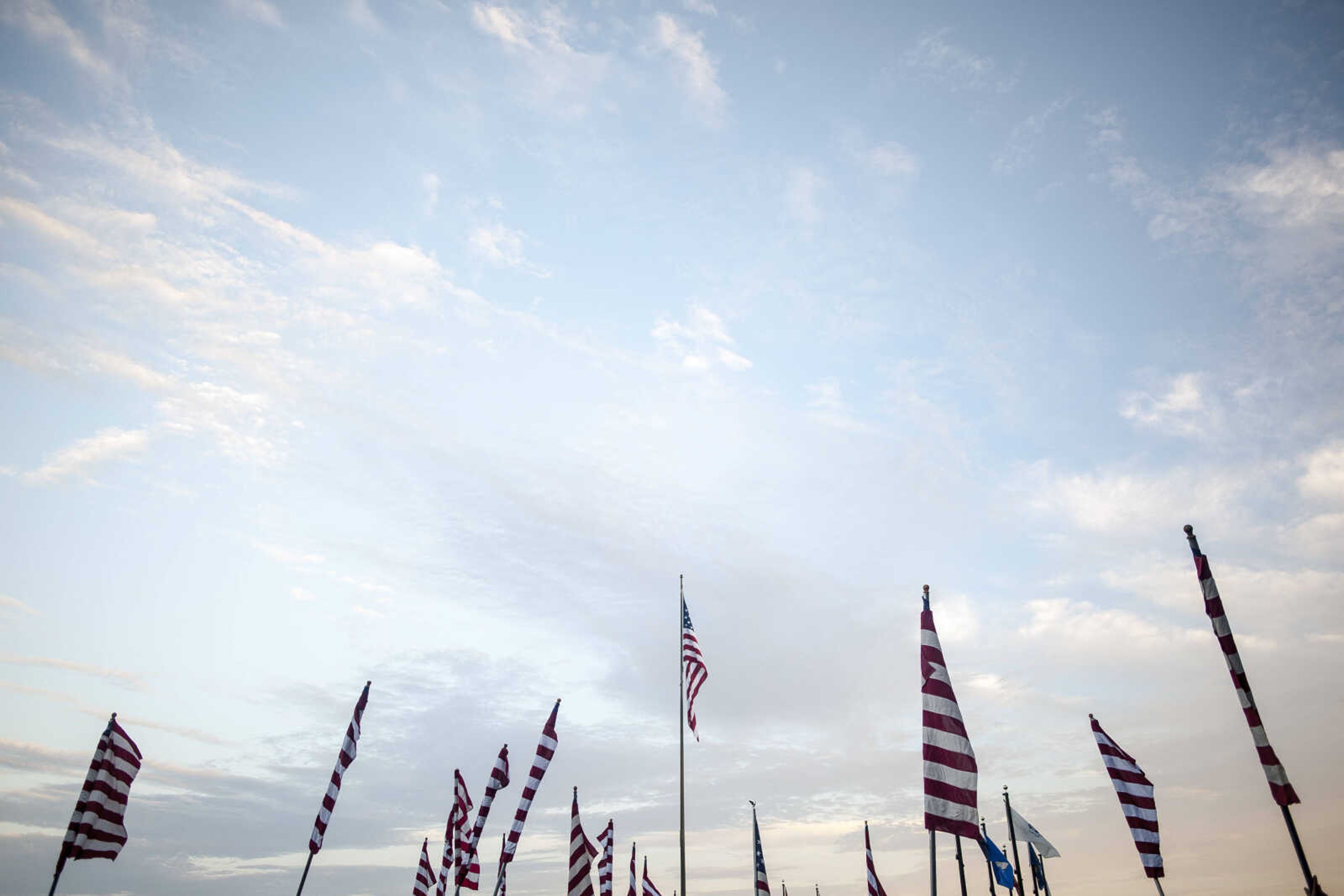 Volunteers carry American flags while the main flag is seen at center Wednesday, July 3, 2019, Avenue of Flags in Cape Girardeau County Park.