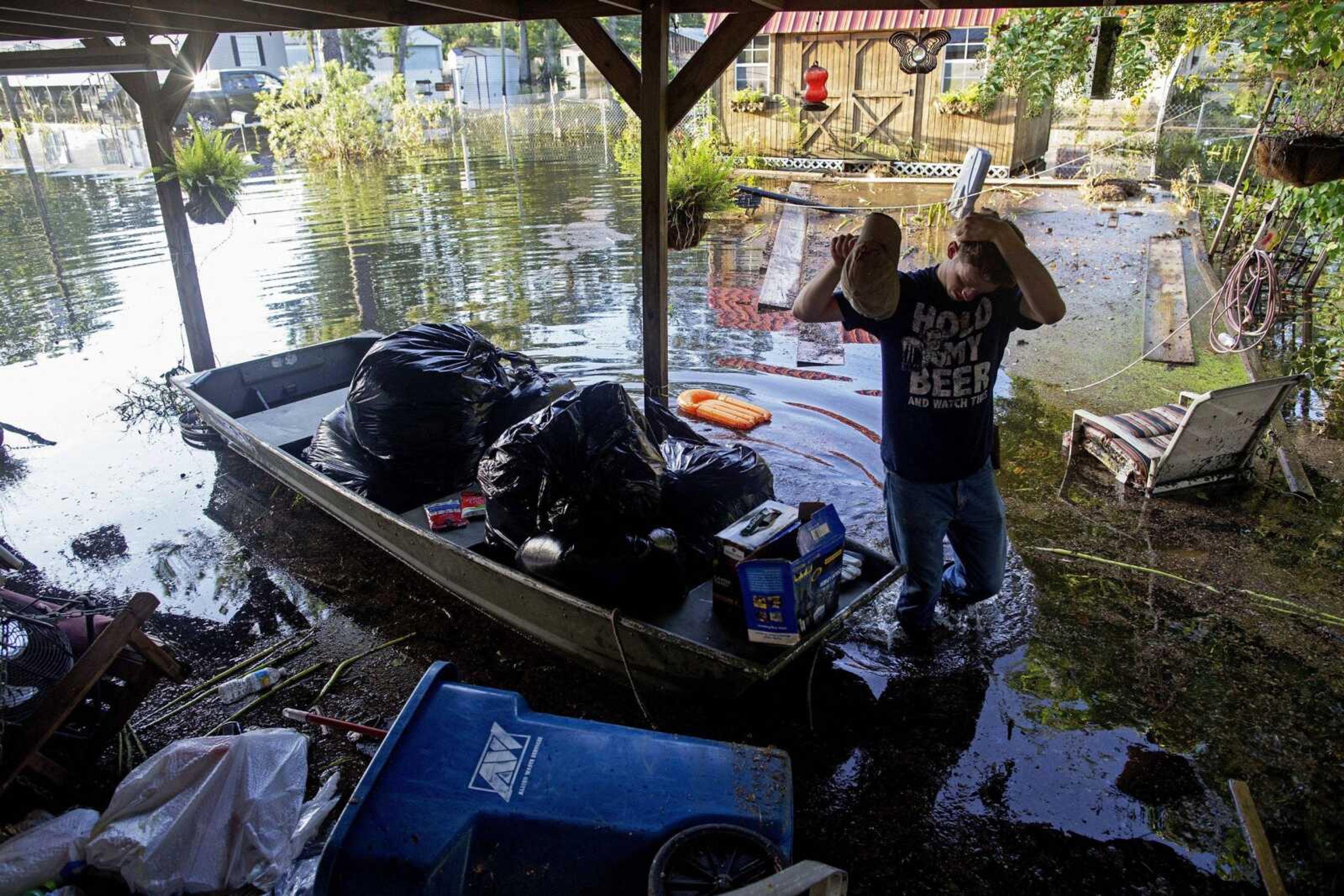 Daniel Stover, 17, wipes his head Saturday as he helps Laura Albritton rescue personal belongings in Sorrento, Louisiana.