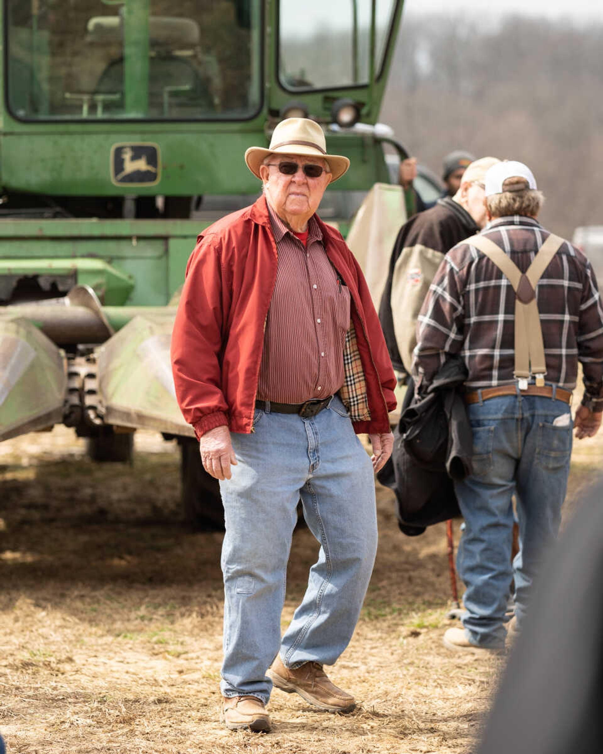 Auctioneer Charley Mangels walks through the farm machinery area while taking a break from auctioneering at an auction in the Fruitland area on March 5, 2022. He says he has made many good friends at sales throughout more than five decades of being an auctioneer.