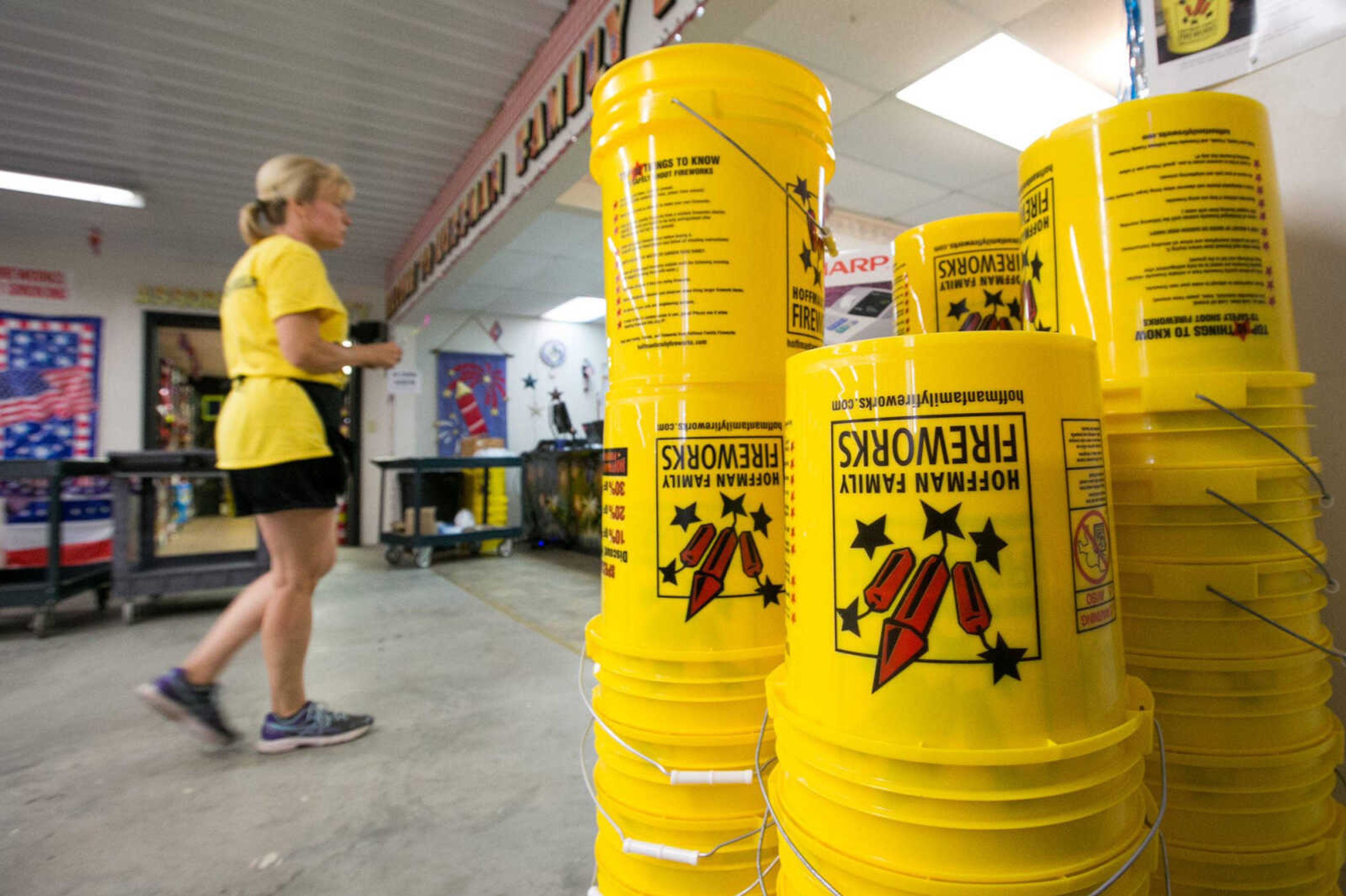 Mary Ann Hoffman moves past a stack of five-gallon safety buckets being handed out at Hoffman Family Fireworks as part of a promotion Thursday in Scott City.