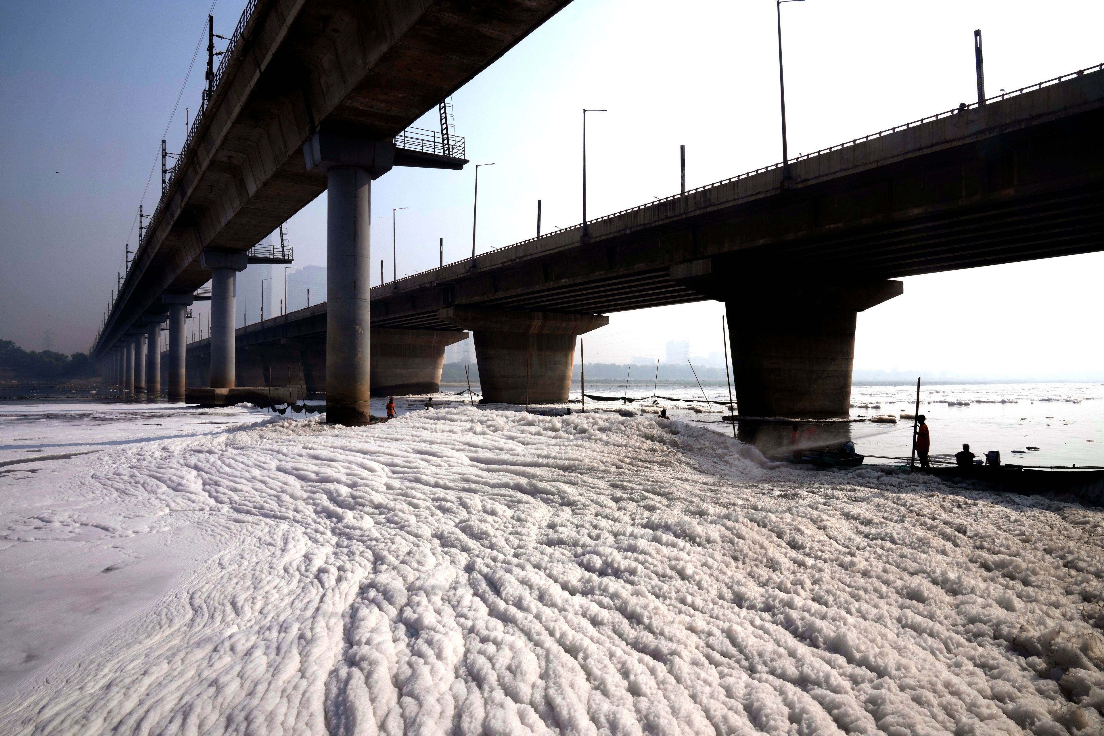 Workers for the Delhi Jal or water board spray chemical to clean the toxic foams in the river Yamuna in New Delhi, India, Tuesday, Oct. 29, 2024. (AP Photo/Manish Swarup)