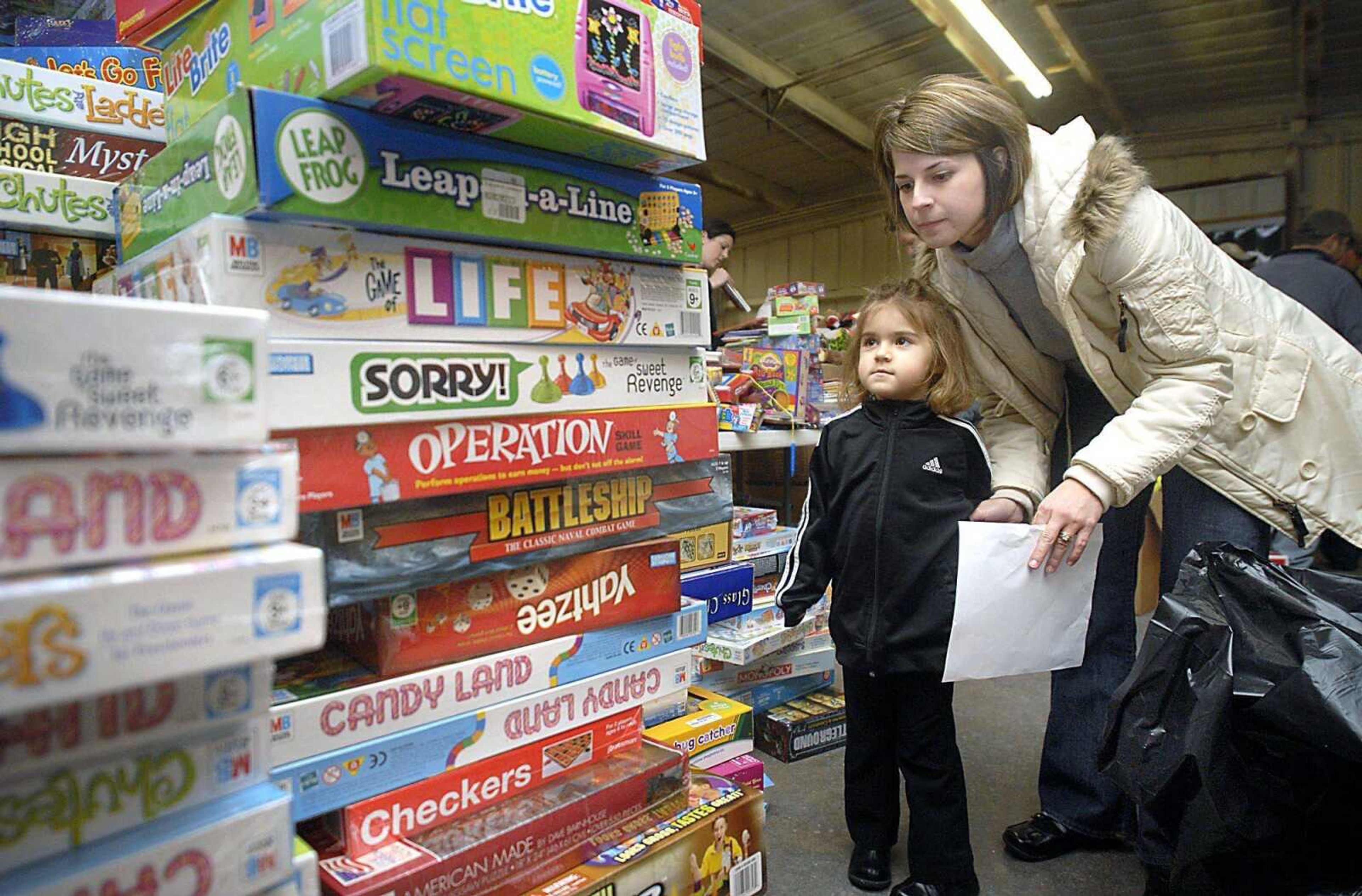 Three-year-old Alexa DeLuca and her mother, Sarah DeLuca, looked for the right board game Tuesday while filling a bag for Toybox.  Today is the final day to donate toys. (Kit Doyle)