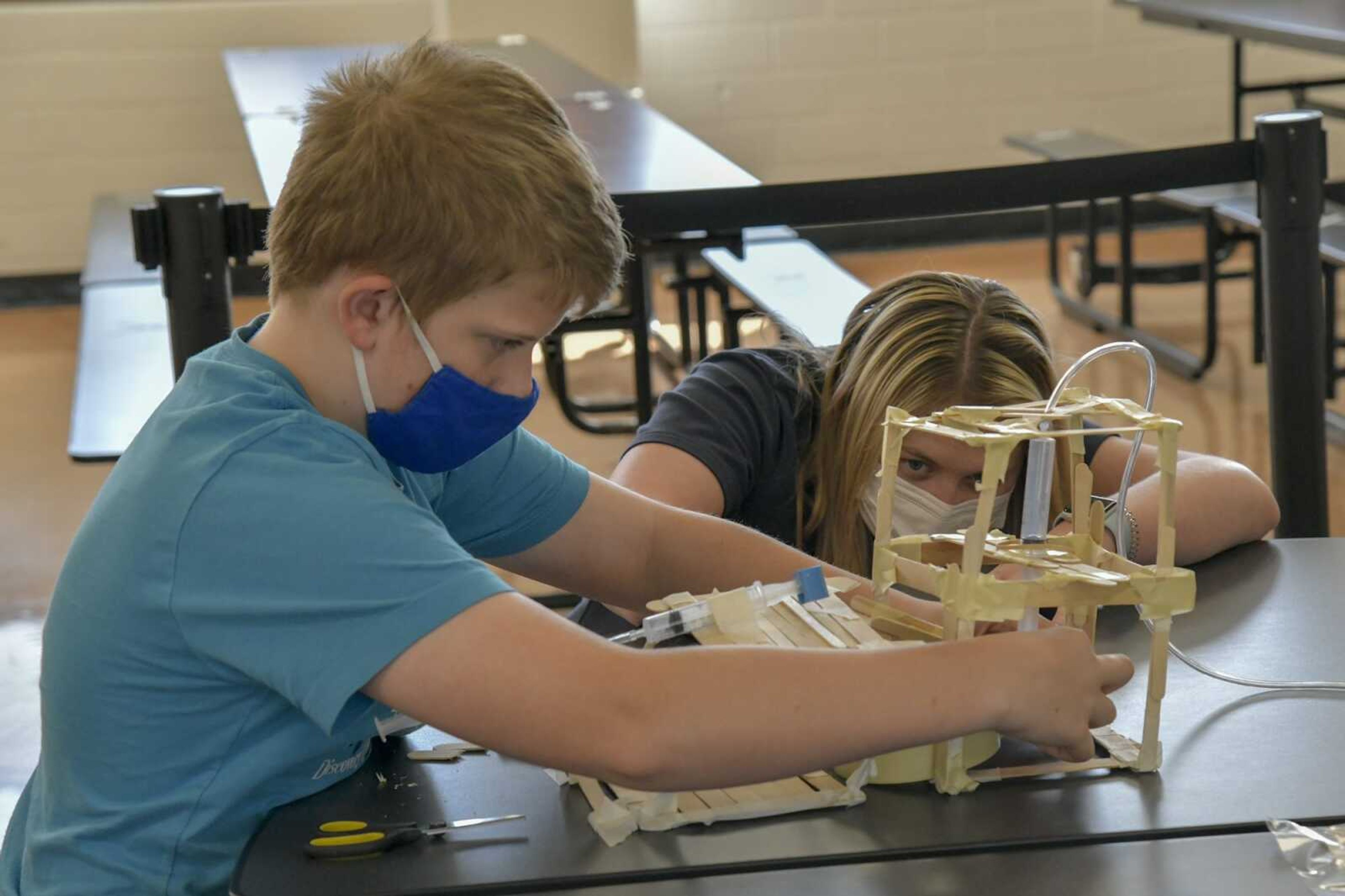 Packaging engineer Rachel Reifsteck, right, helps Tyton Hale, 12, adjust his group's equalizing air pressure system on their group project Thursday at Central Junior High School in Cape Girardeau.