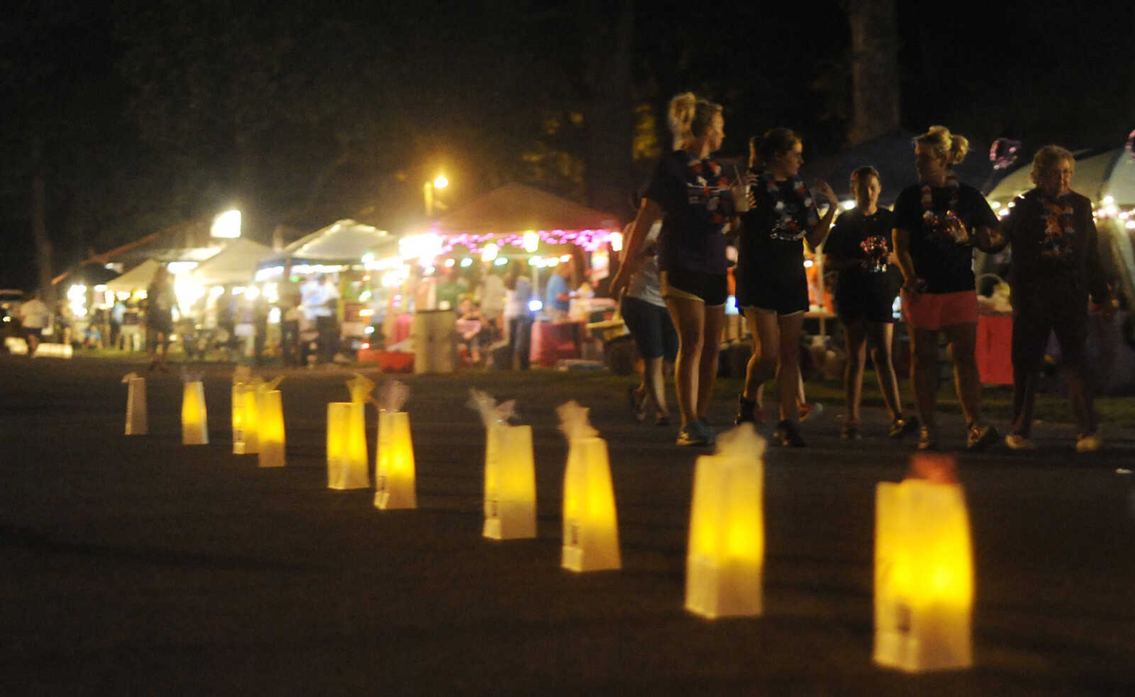 Participants walk past luminaries, paper bags in honor of a cancer survivor or remembrance of friends or family, during the Relay for Life of Cape Girardeau County, Friday, June 14, at Arena Park in Cape Girardeau. This is the 15th year for the event, which serves to raise awareness about cancer while also serving as a fundraiser for the American Cancer Society. Participants form teams which raise money before and during the event.