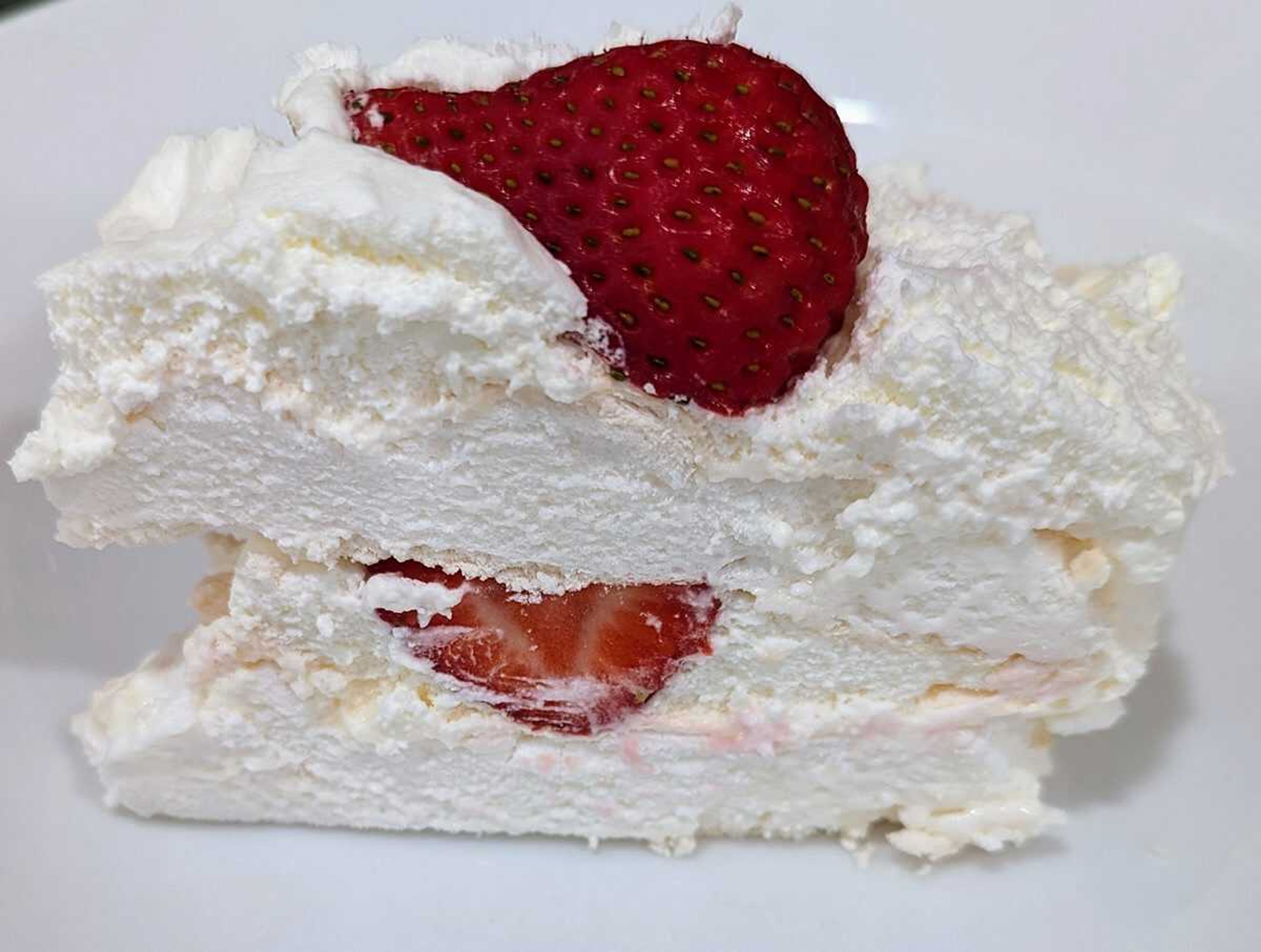 A slice of schaum torte reveals the meringue, whipped cream, and strawberries which together make for a decadent dessert.