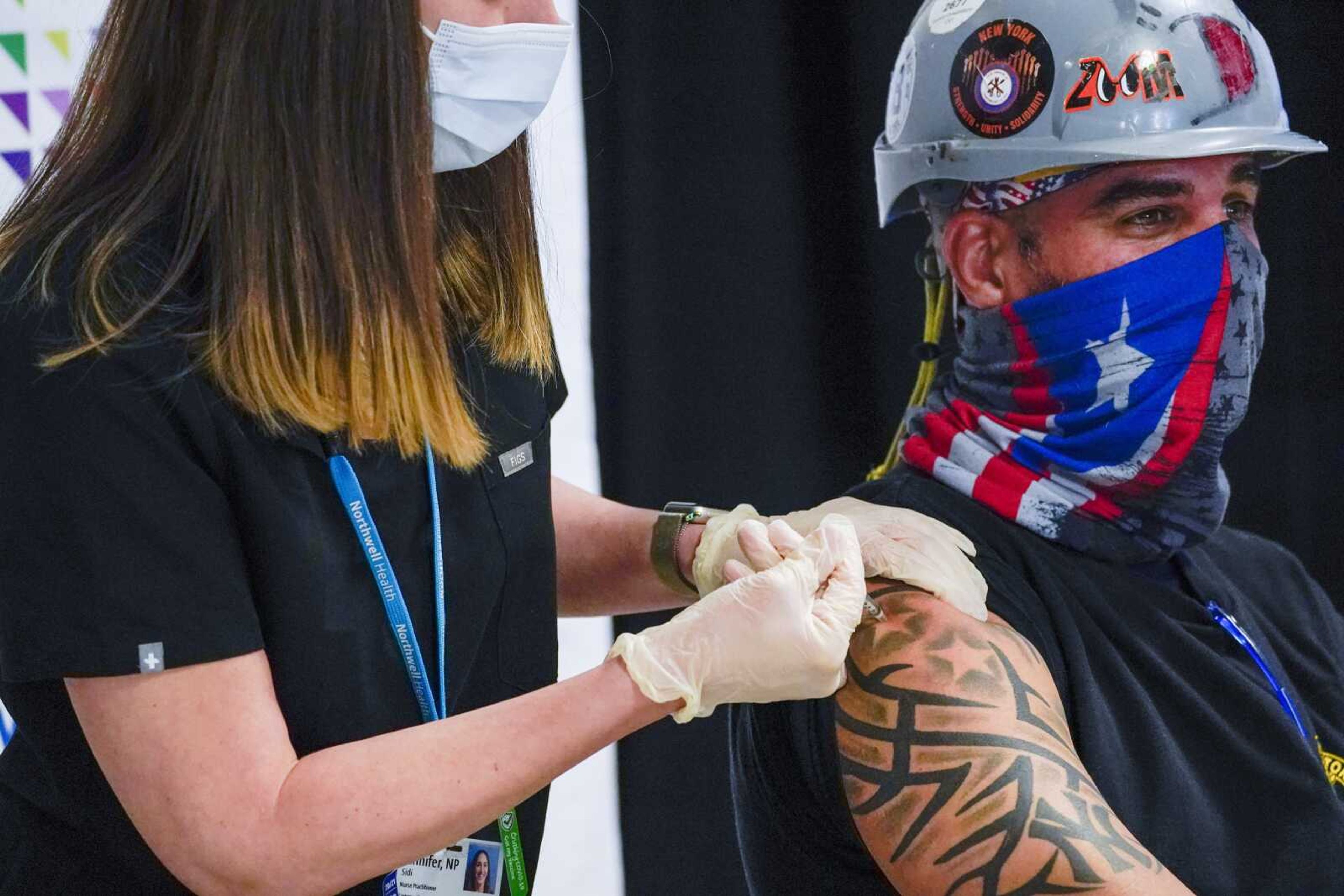 Northwell Health nurse inoculates Local 28 sheet metal worker Demetrius Buttelman with the first dose of the Pfizer vaccine during a news conference Wednesday at Belmont Park in Elmont, New York.