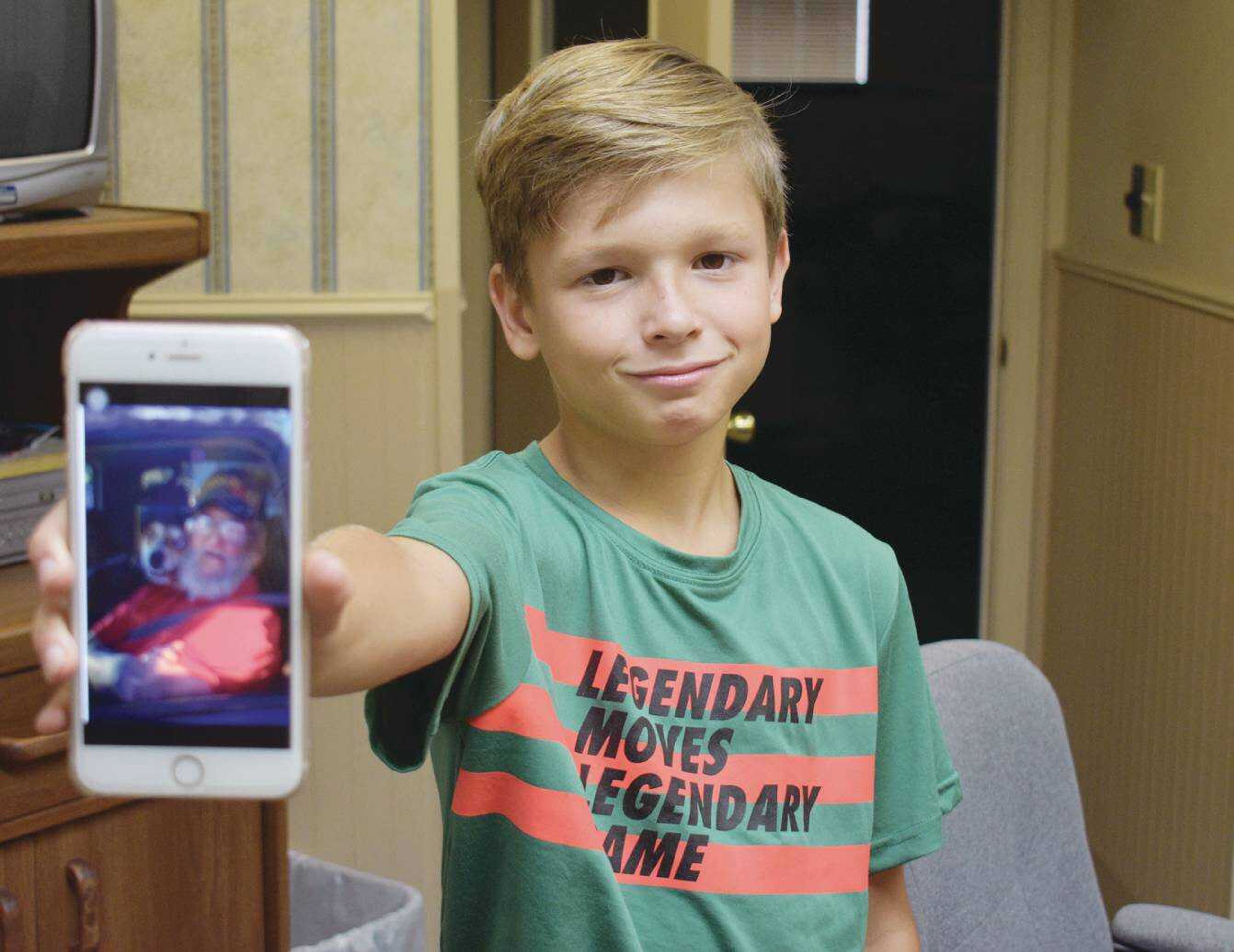 Eli Jenkins, 11, of Butler County, shows a favorite image of his 'PaPa' Wayne Jenkins. The youngster helped pull his grandfather to safety after the family SUV caught fire on Aug. 17.