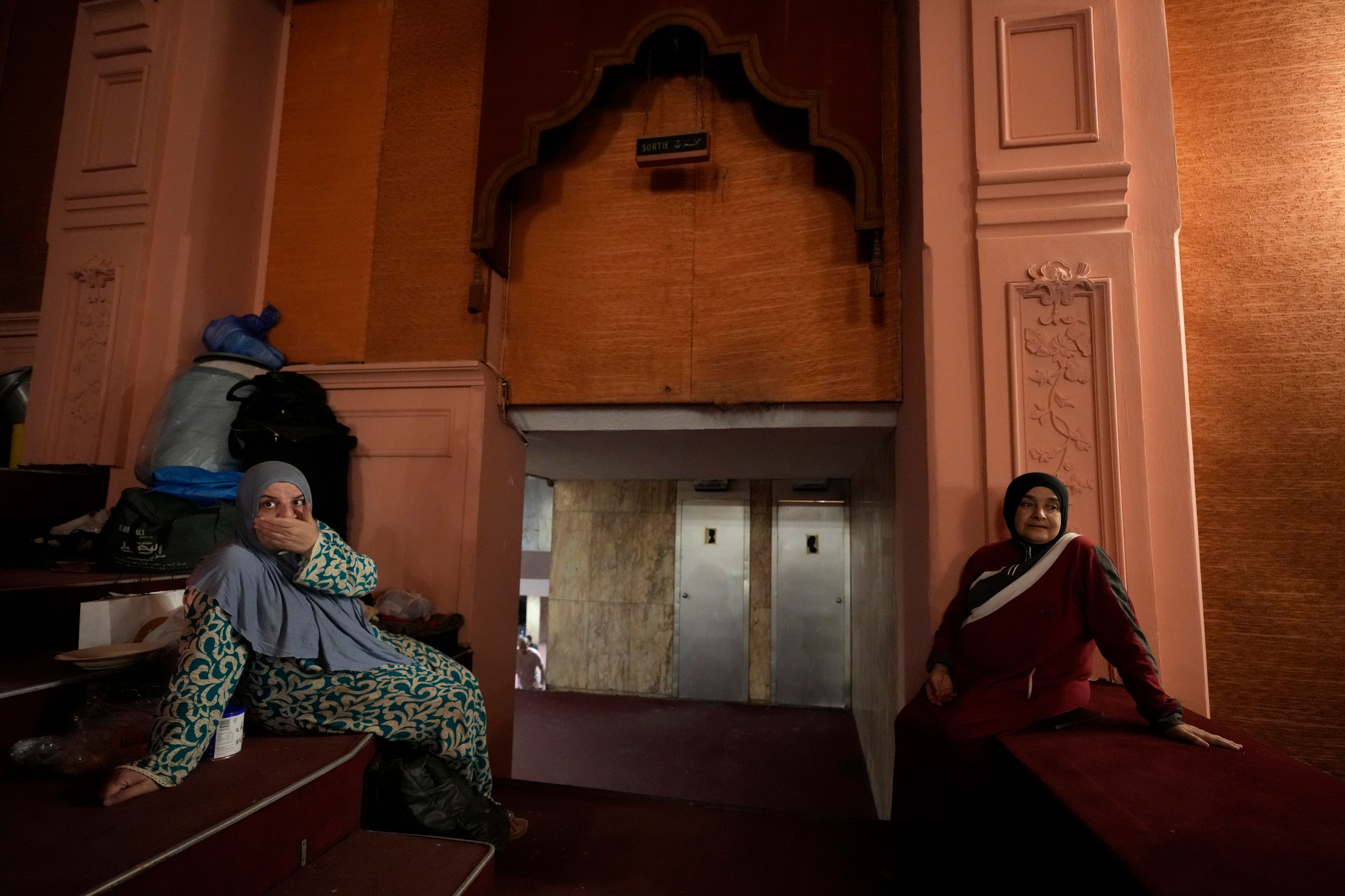 Mona Hanafi, left, and Joumana Hanafi, right, who fled the ongoing Hezbollah-Israel war in south Lebanon, sit inside one of Beirut's oldest and best known movie theaters, Le Colisee, where they are sheltering with their families, in Beirut, Lebanon, Tuesday, Oct. 22, 2024. (AP Photo/Hussein Malla)