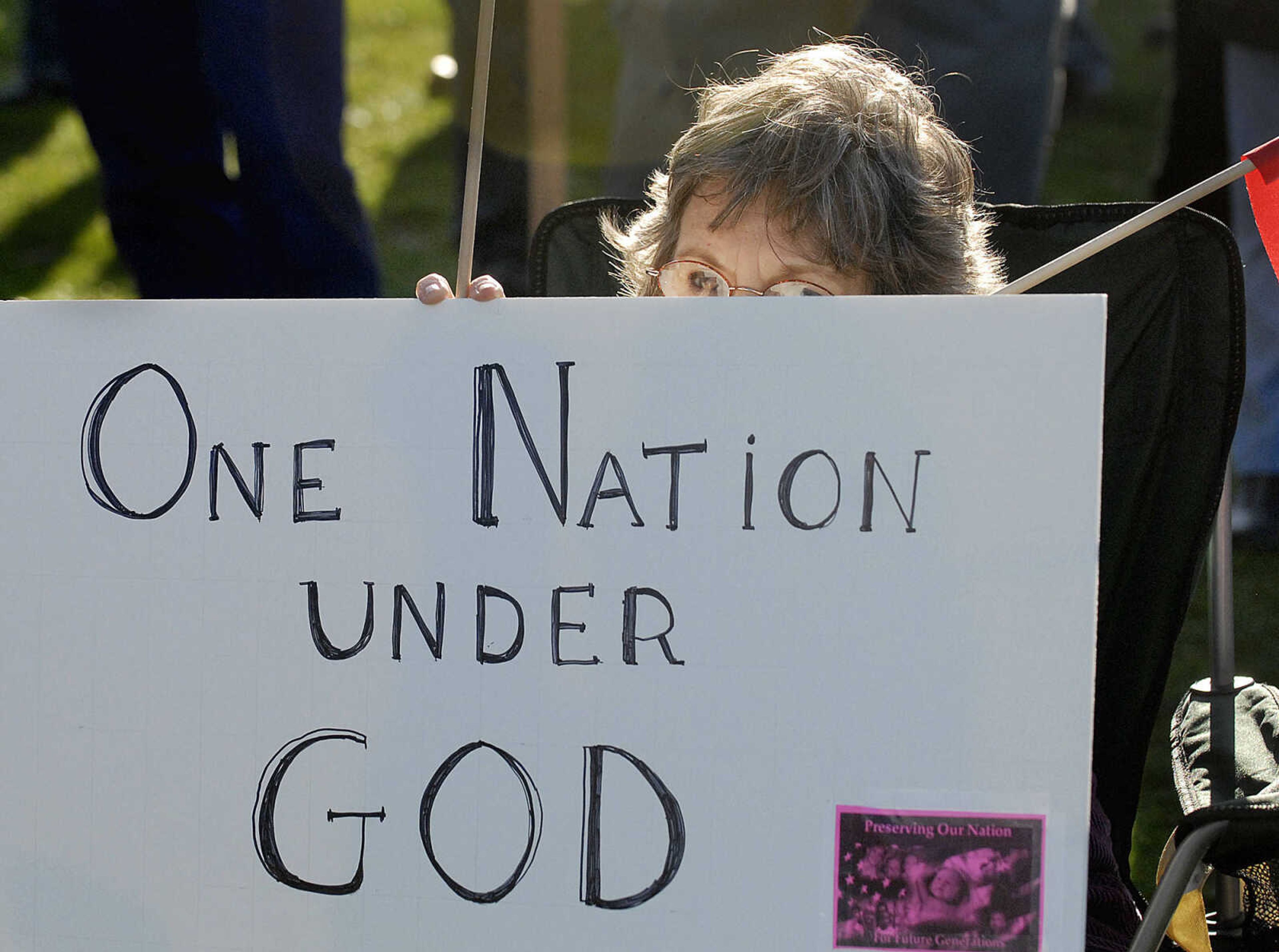 ELIZABETH DODD ~ edodd@semissourian.com
Gerry Hubbs of Altenburg peeks over her sign while listening to speakers at a "tea party" tax protest at Capaha Park Wednesday.