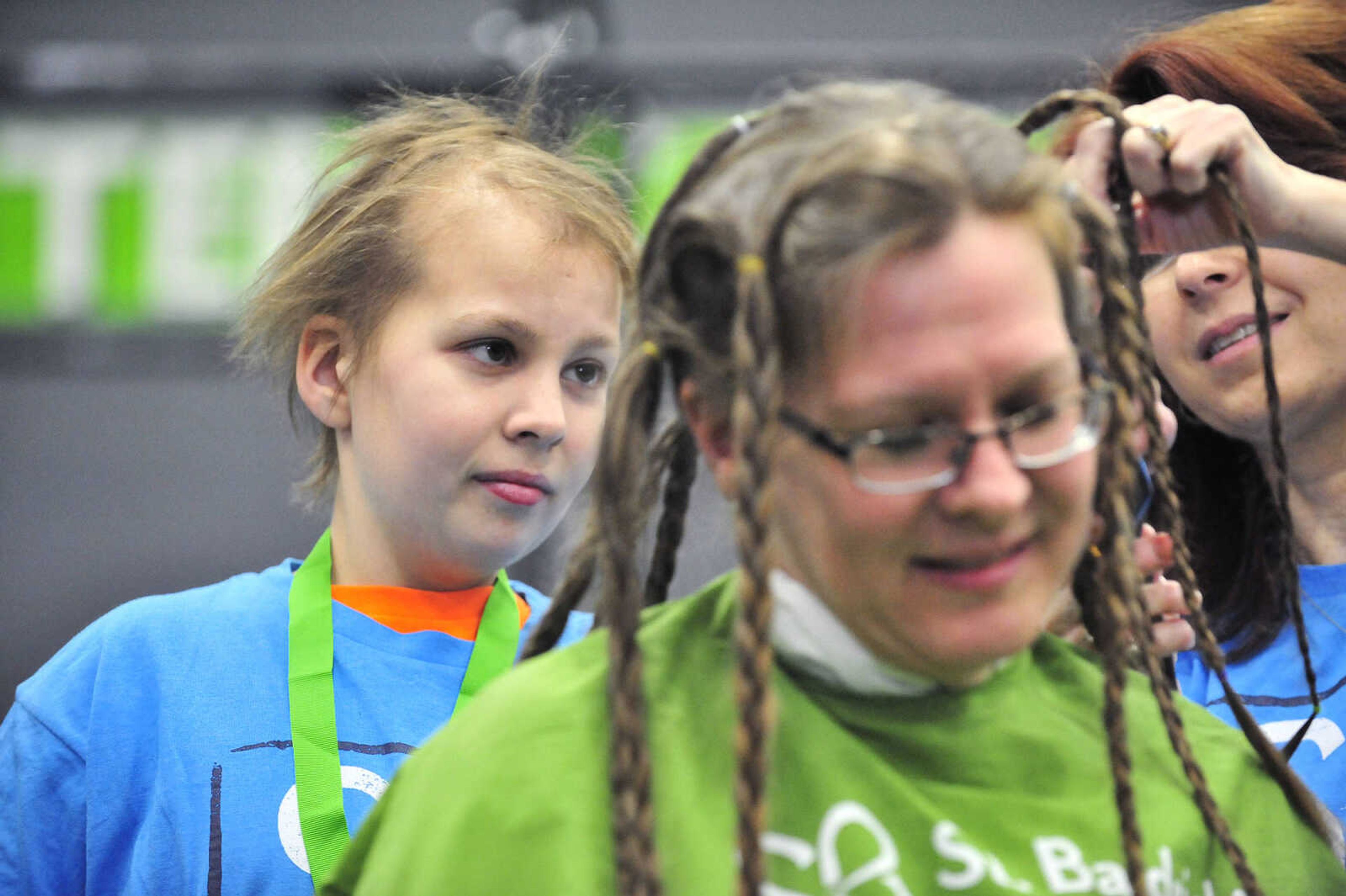 Sarah Singleton, 13, shaves part of her mother's, Jennifer, hair off with assistance from April Whiteside on Saturday, March 4, 2017, during the St. Baldrick's Foundation fundraiser at Old Orchard CrossFit in Jackson.