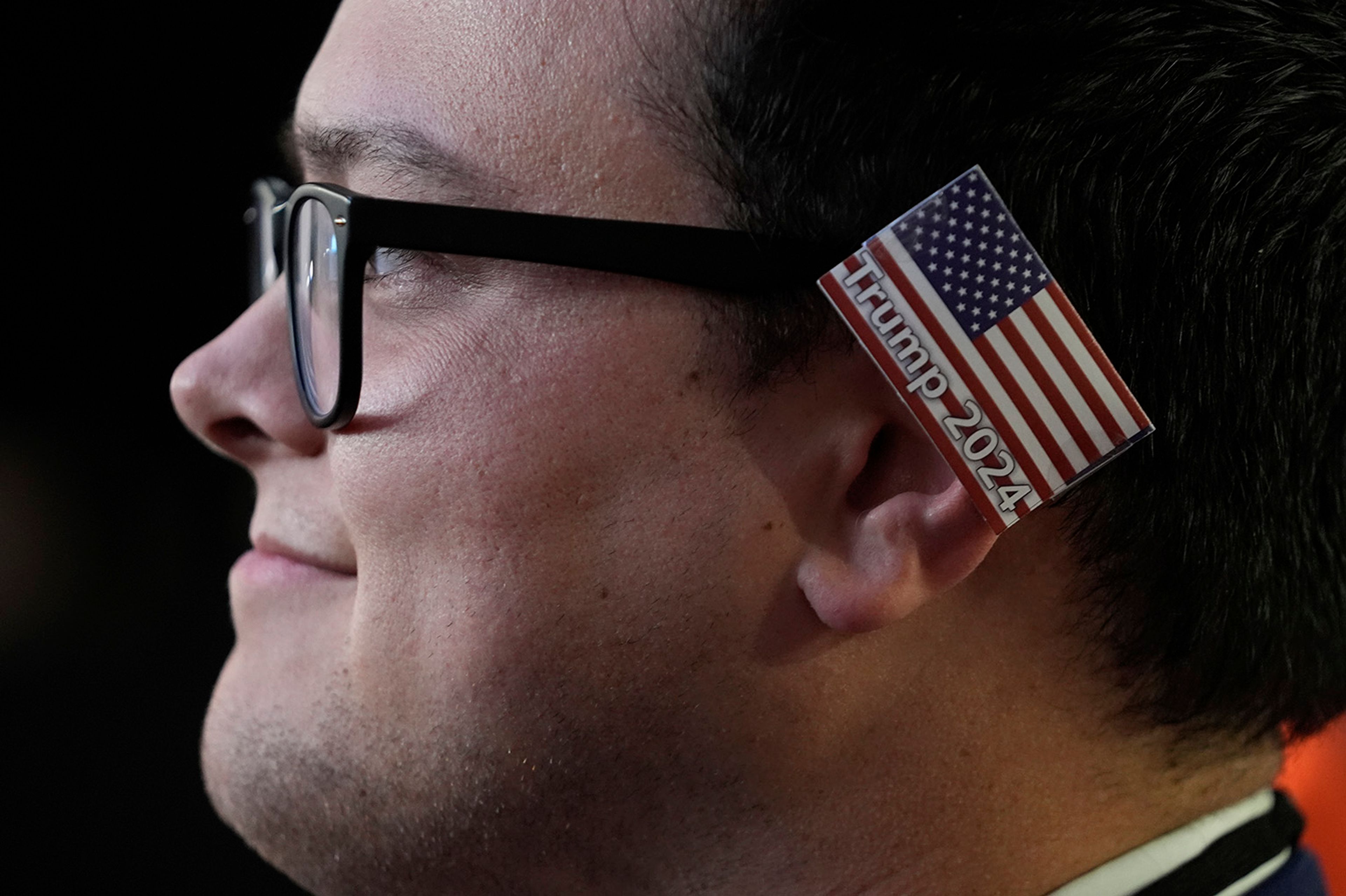 A delegate wearing a small American flag on his ear watches as Republican presidential candidate and former president, Donald Trump, speaks during the final day of the Republican National Convention Thursday, July 18, 2024, in Milwaukee. 