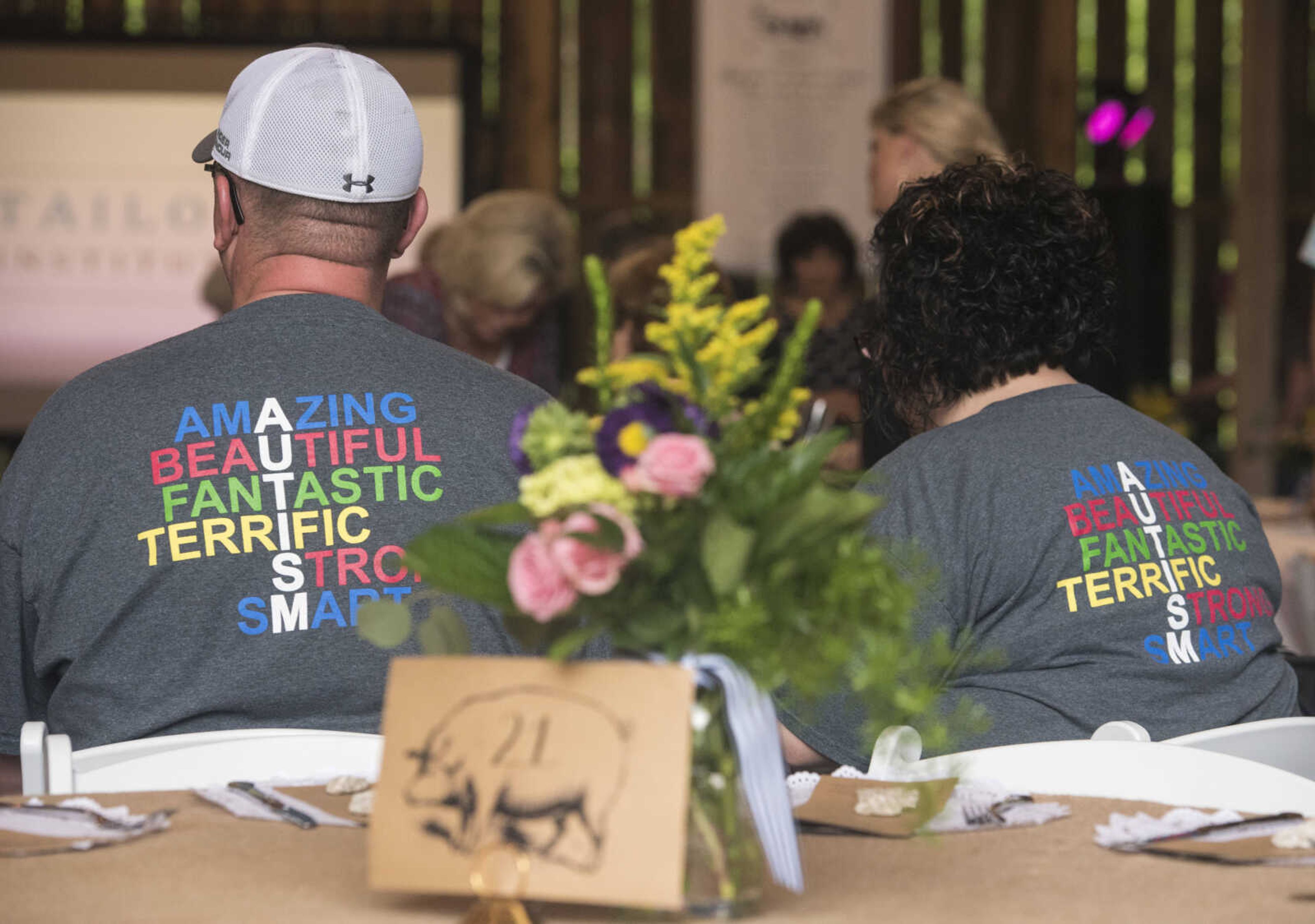 Guests wear autism awareness shirts at Rusted Route Farms on April 29, 2017 during a Swine & Dine pig roast benefiting The Tailor Institute.