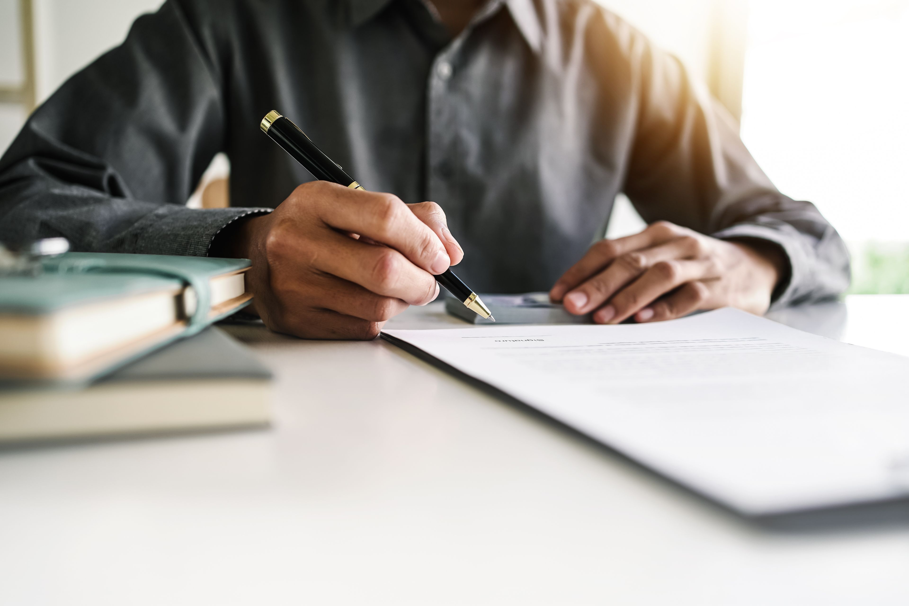 Close up businessman sign a contract, holding pen, sitting in office.