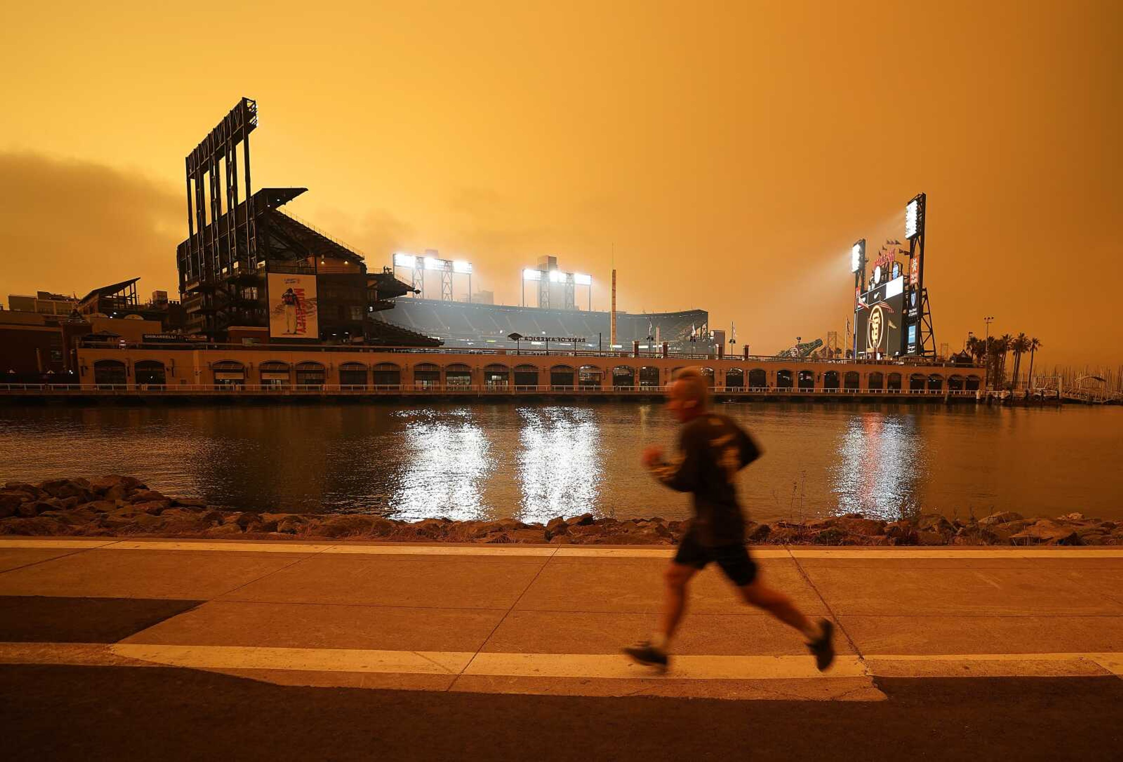 A jogger runs along McCovey Cove outside Oracle Park on Sept. 9 in San Francisco, under darkened skies from wildfire smoke.