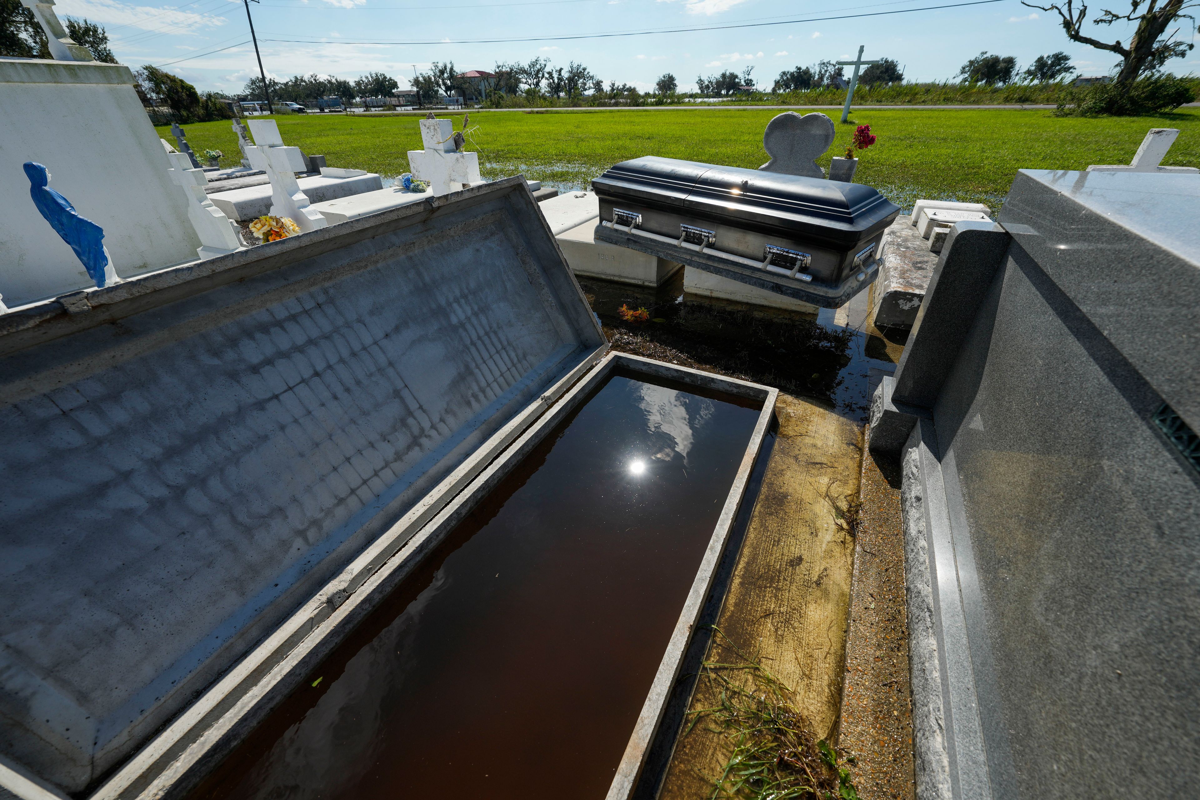 A casket sits on an adjacent tomb after floating out of its tomb at Holy Family Cemetery No. 2, Thursday, Sept. 12, 2024, Dulac, La., following floodinig from Hurricane Francine. (AP Photo/Gerald Herbert)