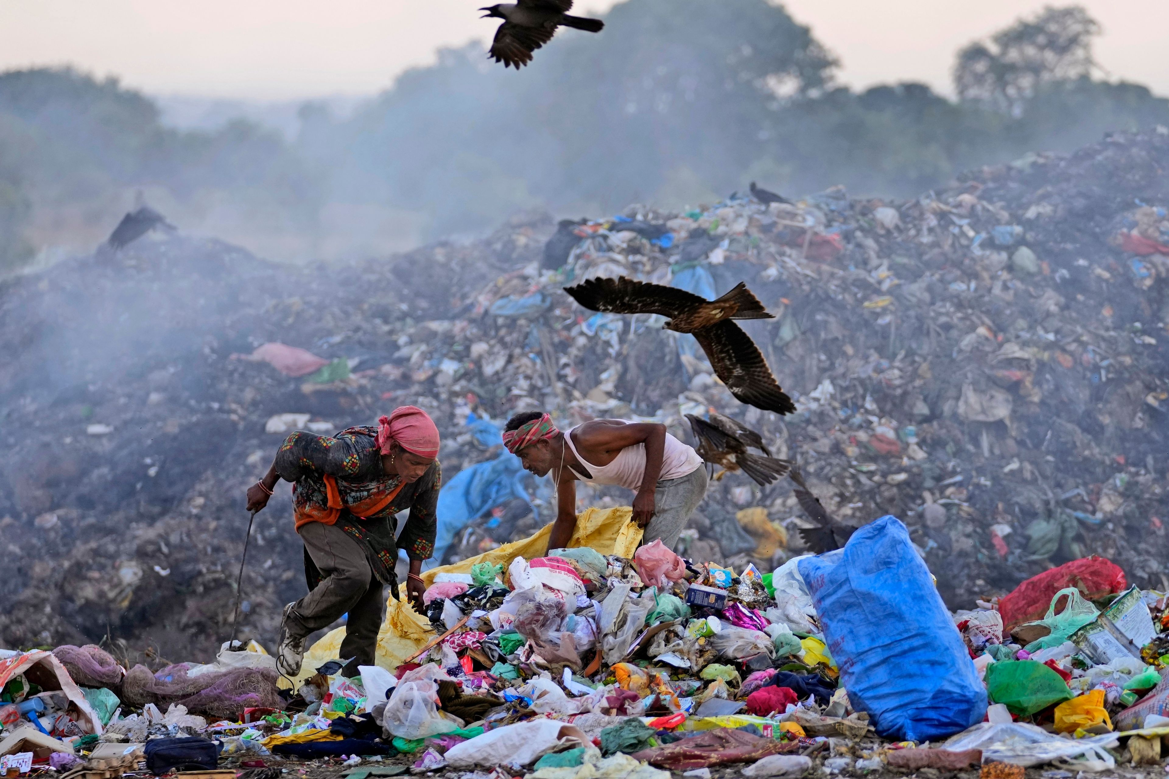 FILE- Waste pickers Salmaa and Usmaan Shekh, right, search for recyclable materials during a heat wave at a garbage dump on the outskirts of Jammu, India, Wednesday, June 19, 2024. (AP Photo/Channi Anand, File)