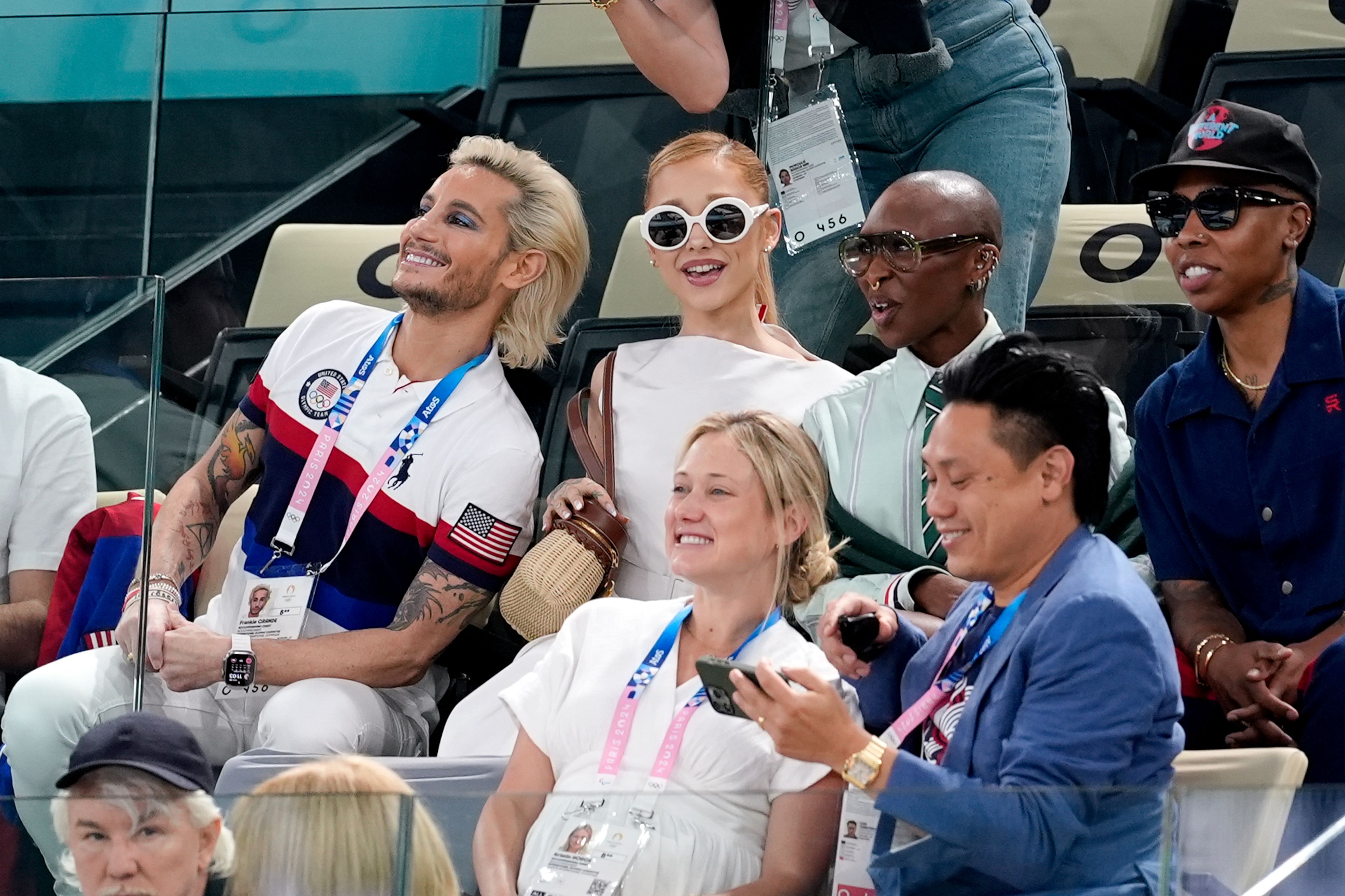 FILE - Frankie Grande, from left, Ariana Grande, Cynthia Erivo, and Lena Waithe, attend the women's artistic gymnastics qualification round at the 2024 Summer Olympics, Sunday, July 28, 2024, in Paris, France. In “Wicked,” Elphaba and Glinda travel from Shiz University to the Emerald City on a glistening green train to meet the wizard. In real life, Cynthia Erivo and Ariana Grande have traveled much farther and wider and longer and on airplanes to promote their hotly anticipated film. (AP Photo/Abbie Parr, File)