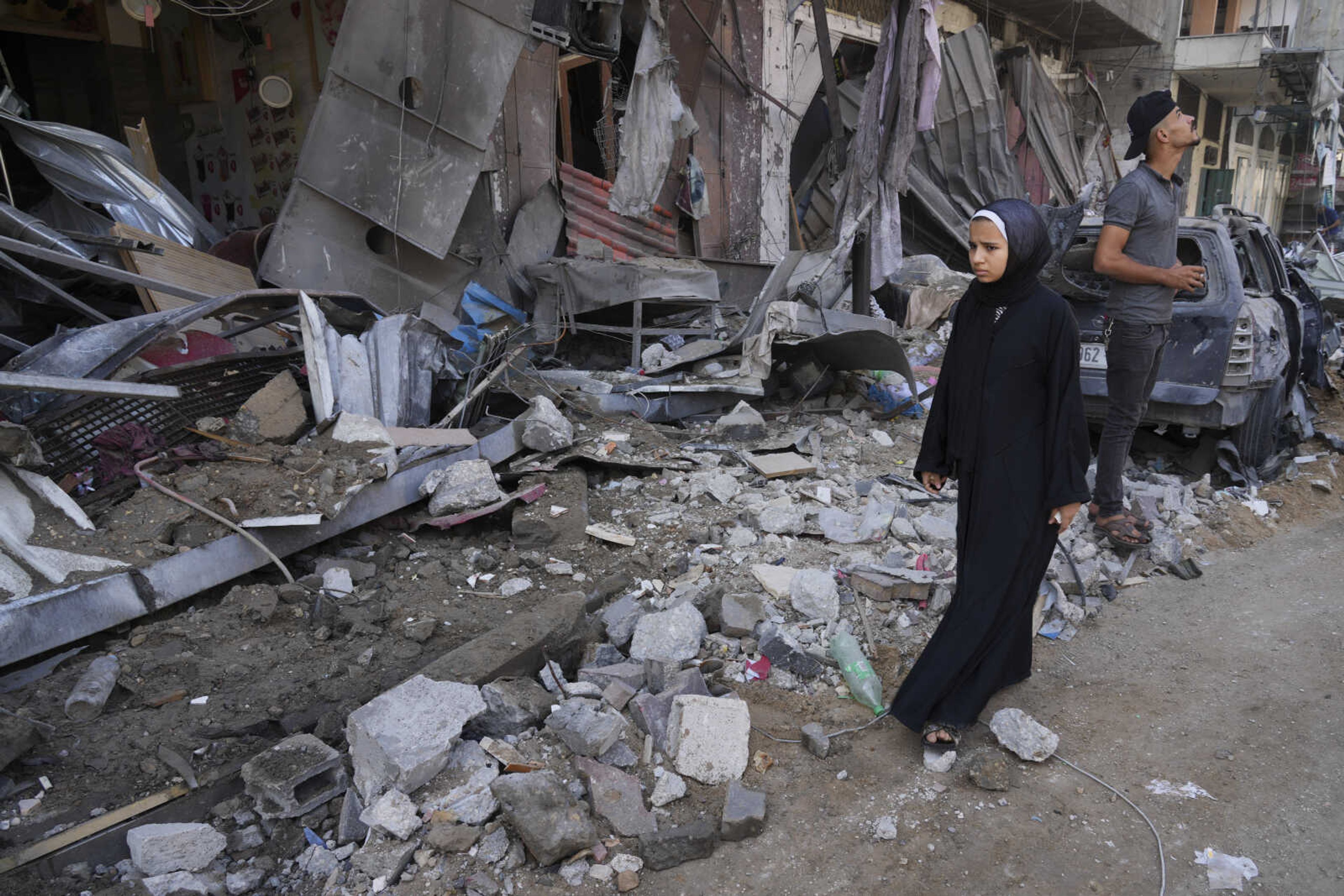 Palestinians walk by destruction by the Israeli bombardment of the Gaza Strip in the Maghazi refugee camp, in Deir Al-Balah, Wednesday, Oct. 25, 2023. ( AP Photo/Hatem Moussa)