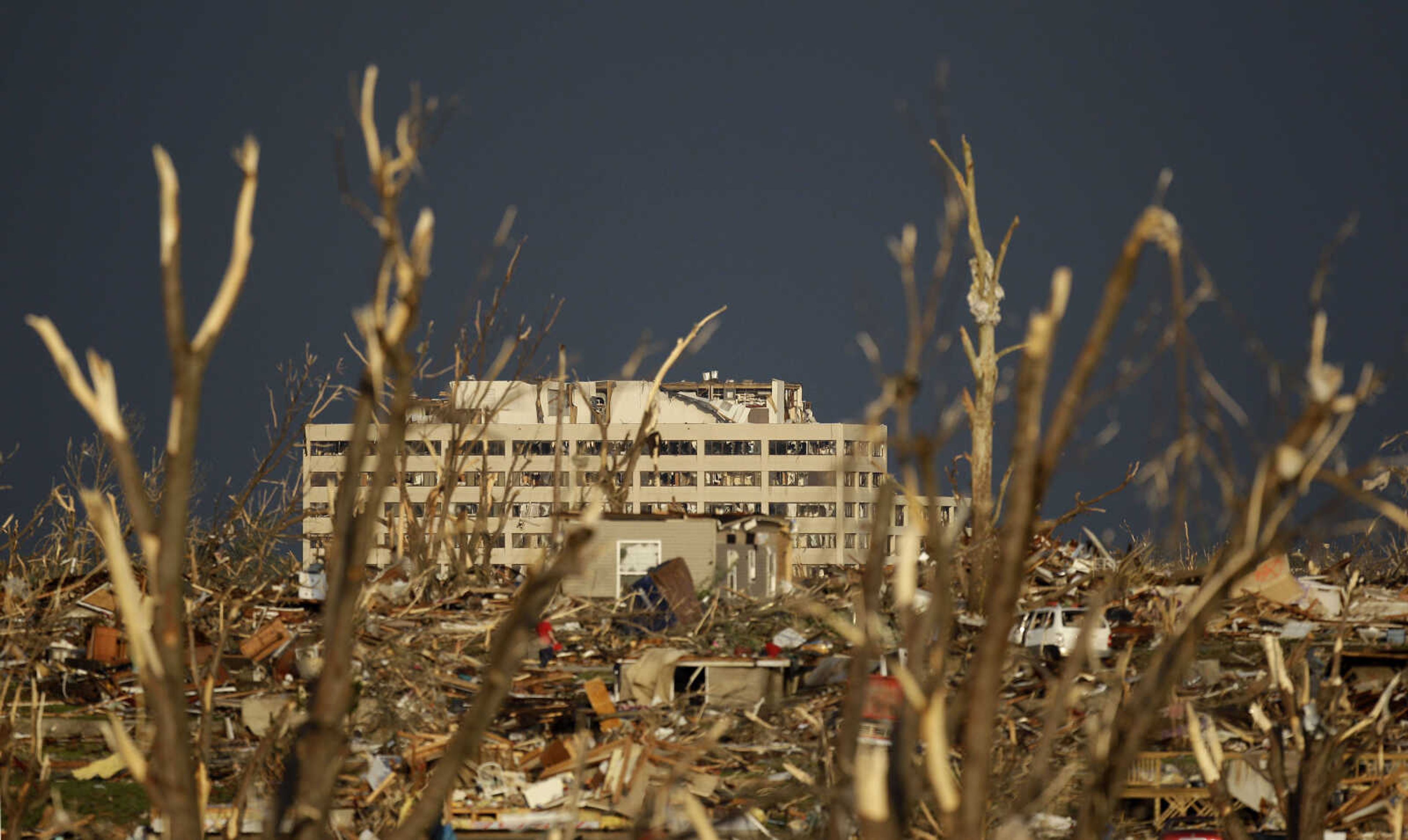 The damaged St. John's Regional Medical Center is seen in the distance through tornado debris in Joplin, Mo., Monday, May 23, 2011. A large tornado moved through much of the city Sunday, damaging the hospital and hundreds of homes and businesses and killing at least 89 people. (AP Photo/Charlie Riedel)