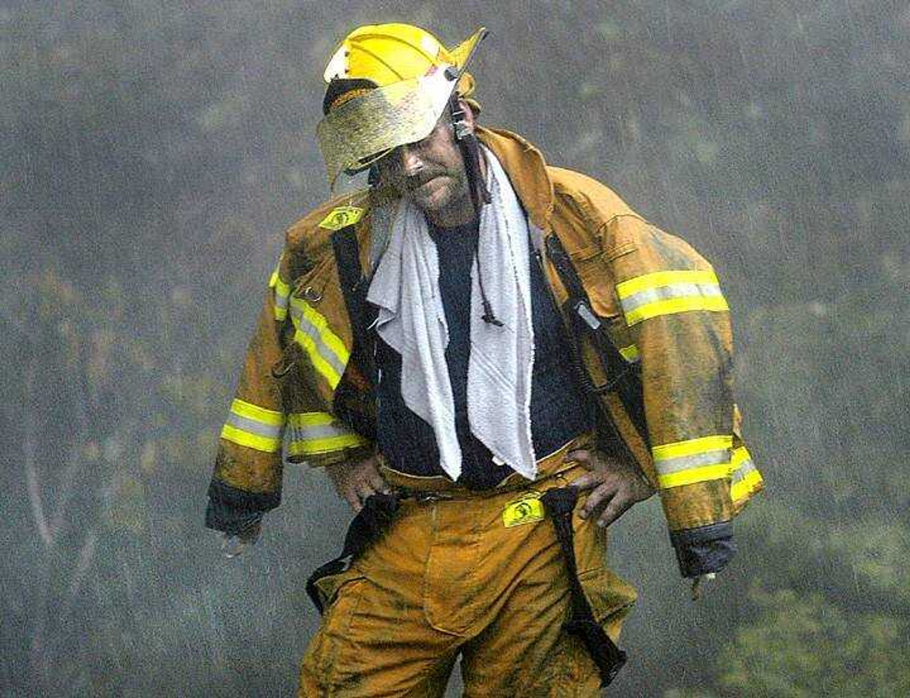 A Scott City fire firefighter shielded his face with his helmet from the rain that came through during a fire at 1725 Hilleman St. in Scott City, Thursday, Aug. 10, 2006.