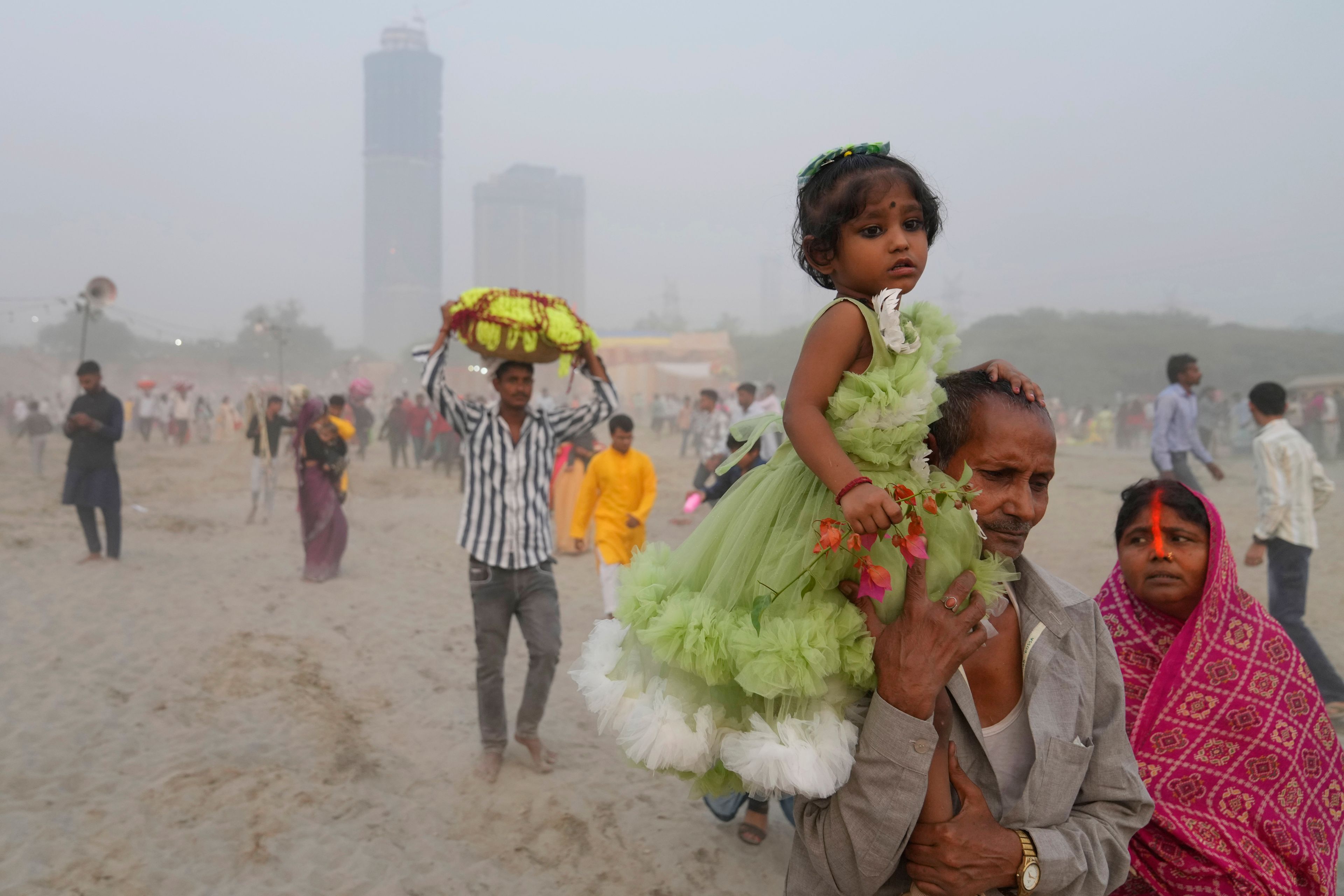 Devotees arrive on the banks of the river Yamuna to offer prayers as smog envelops the skyline during the Chhath festival in Noida, near New Delhi, India, Thursday, Nov. 7, 2024. (AP Photo/Manish Swarup)