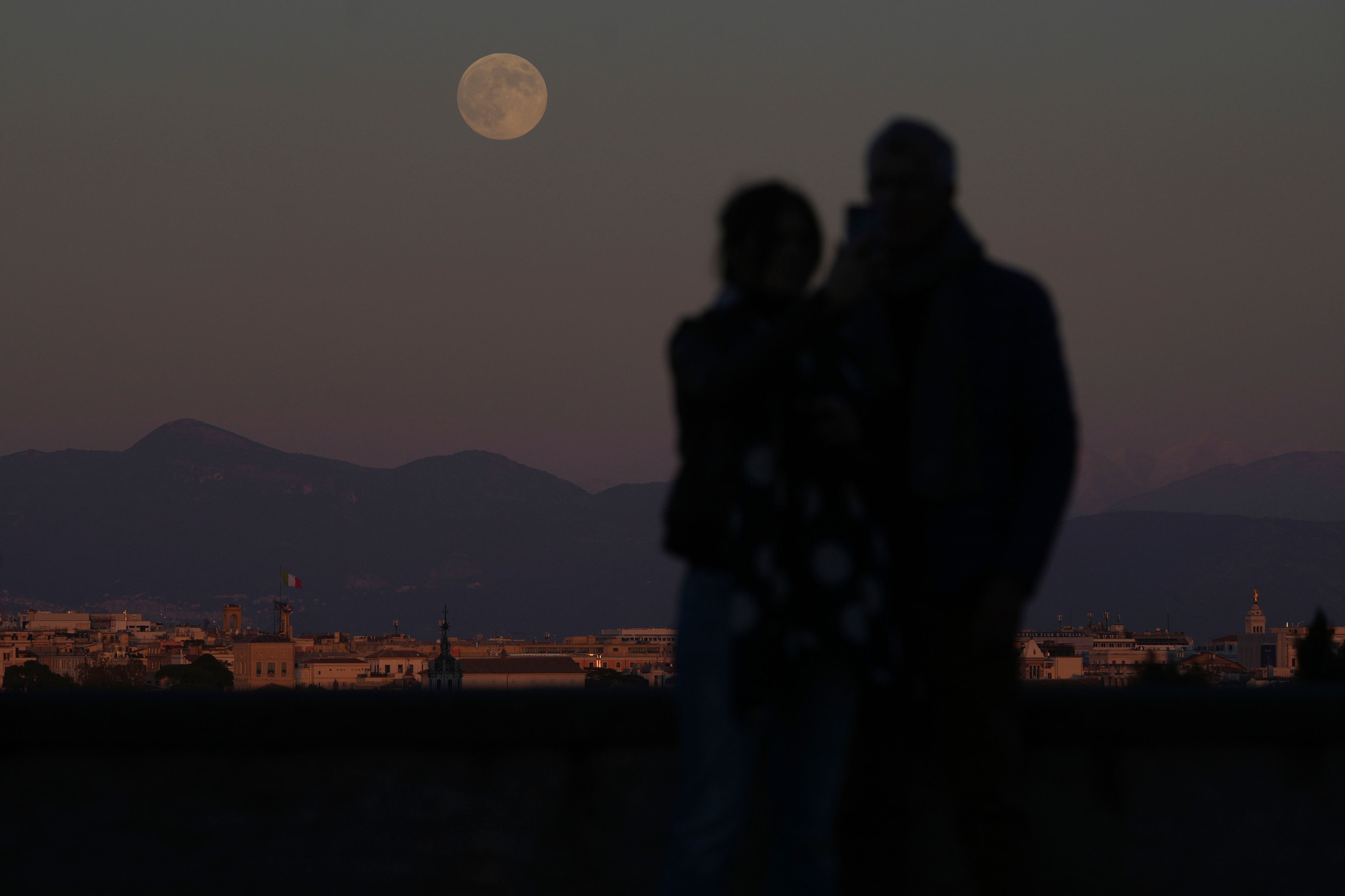 People watch at the full moon rising over Rome, Friday, Nov. 15, 2024. (AP Photo/Alessandra Tarantino)