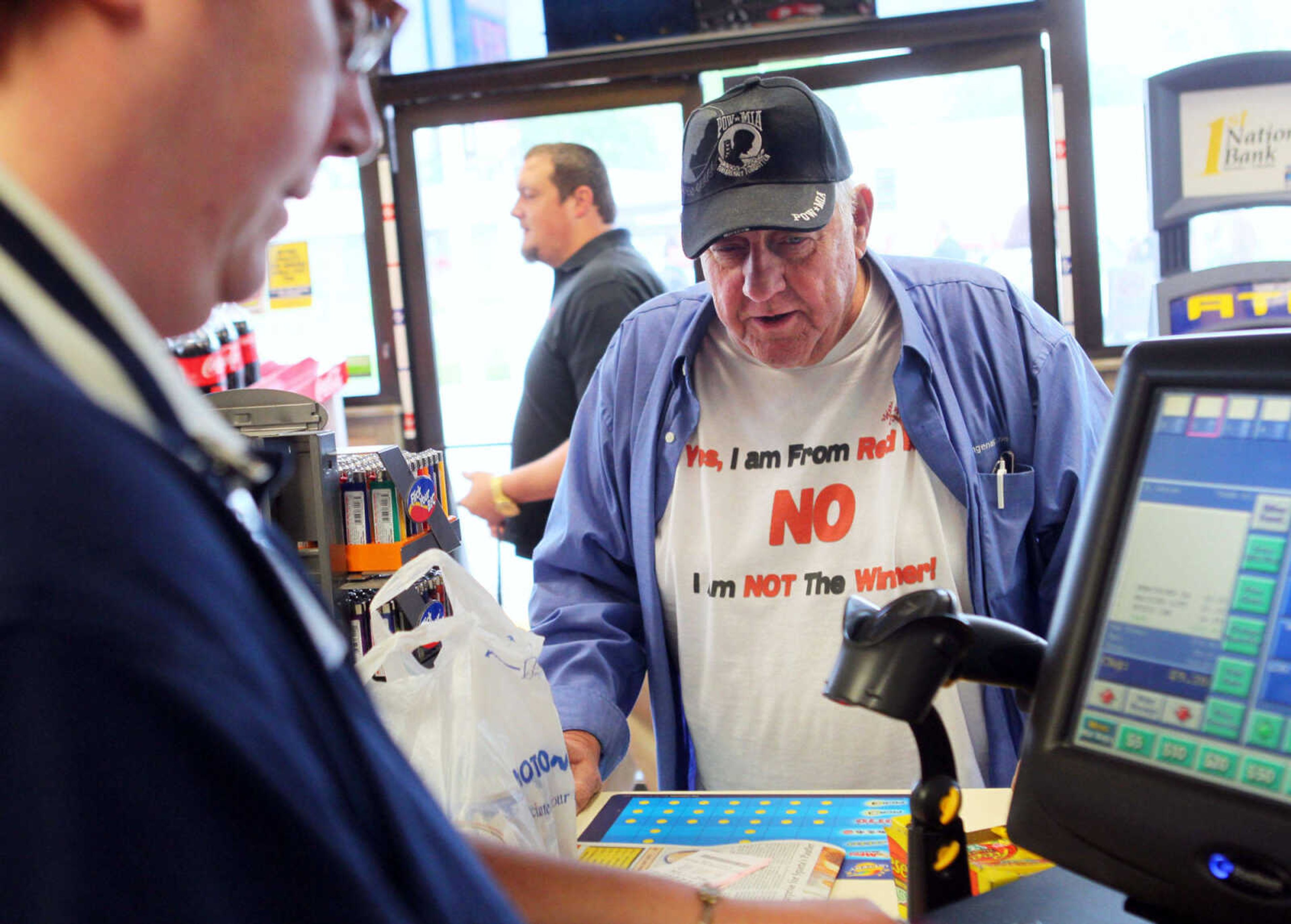 John Daffron, wearing a shirt that reads "Yes, I am from Red Bud. No I am NOT the Winner!" buys a lottery ticket at the MotoMart that sold one of three tickets that won a share of world-record $656 million Mega Millions jackpot, on Thursday, April 5, 2012 in Red Bud, Ill. (AP Photo/St. Louis Post-Dispatch, Emily Rasinski)