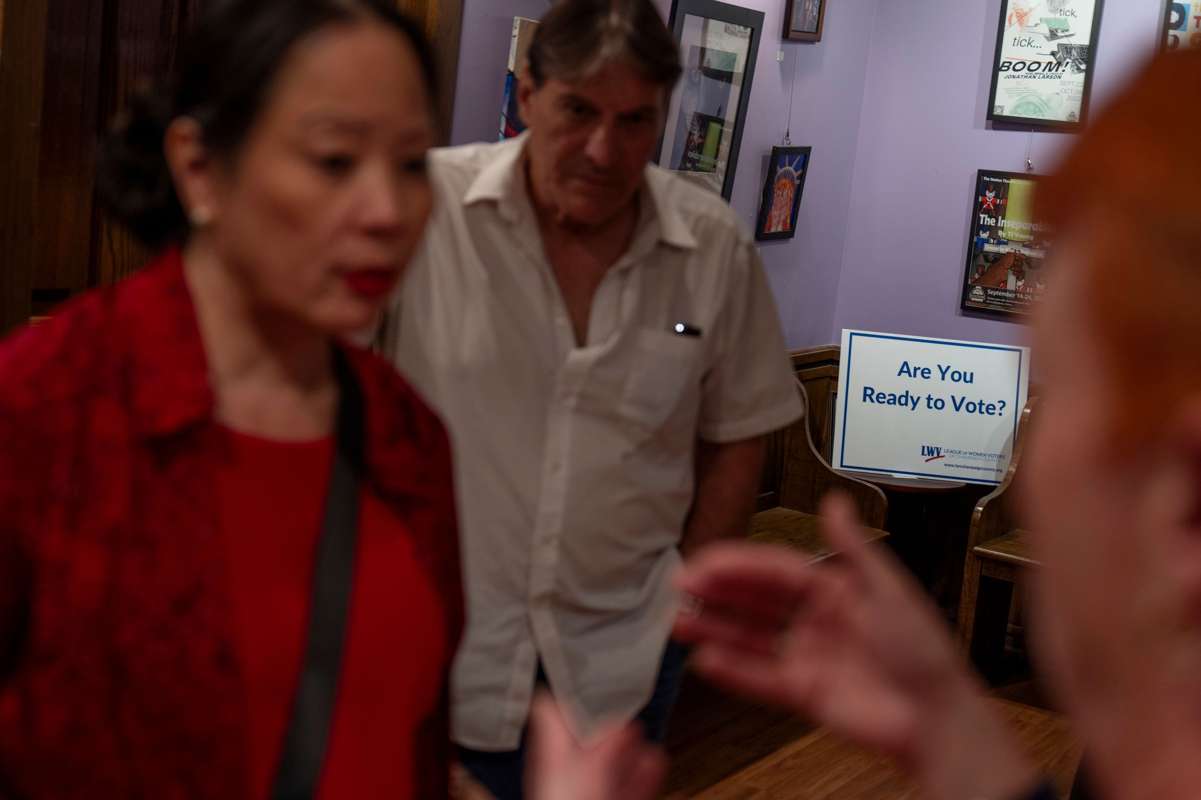 A sign encouraging voting sits behind Lesley Dzik, left, and her husband, Matt, in the lobby of The Station Theatre as they volunteer as ushers during a performance of "POTUS: Or, Behind Every Great Dumbass Are Seven Women Trying to Keep Him Alive," in Urbana, Ill., Saturday, Sept. 21, 2024. (AP Photo/David Goldman)