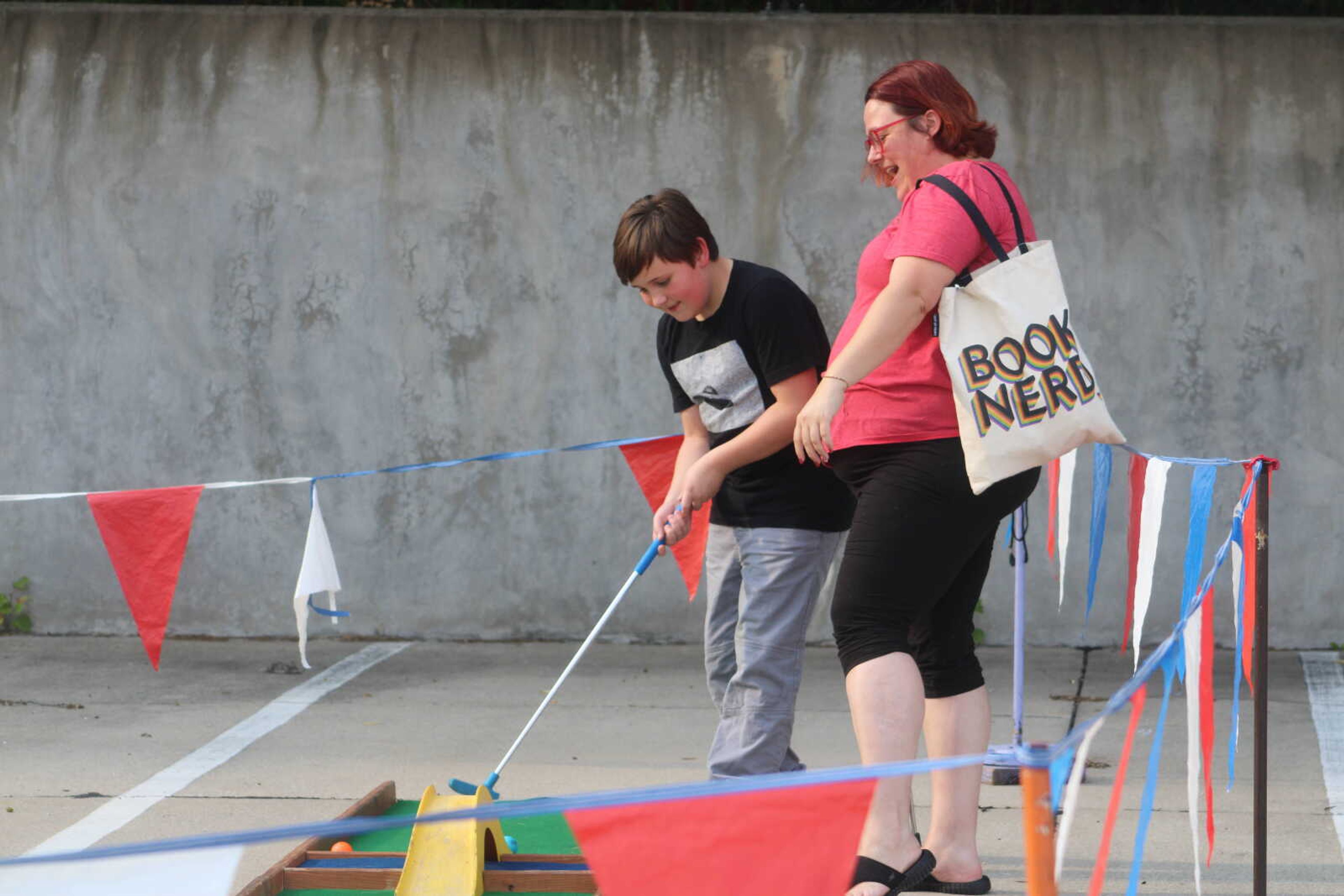 Robbie Huntington, left, attempts a shot in mini golf as his mother, Diane, stands beside him and laughs during the Cape Broadway Theatre Festival on Saturday, July 18, 2021, in the parking lot on the northeast corner of Broadway and Pacific Street in Cape Girardeau.