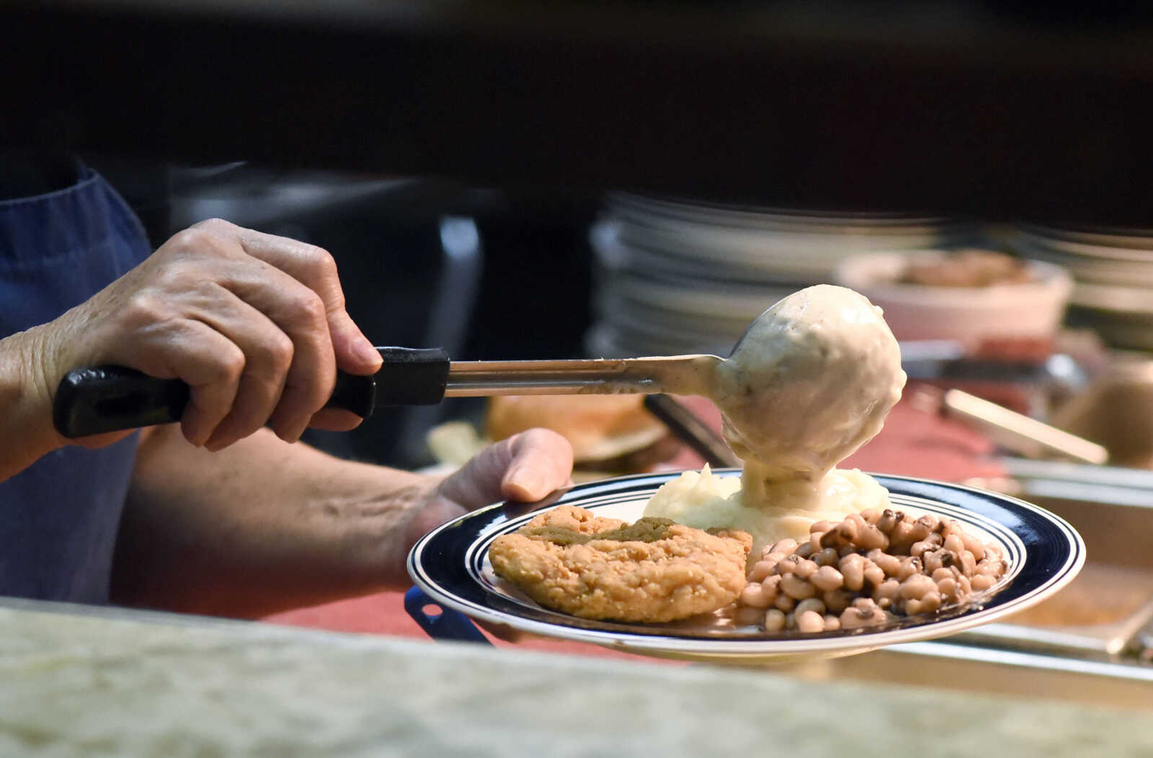 Vickie Miinch tops a chicken fried steak lunch special with homemade gravy on Monday, March 27, 2017, at Bonnie's Moo Cow Cafe in Patton, Missouri.