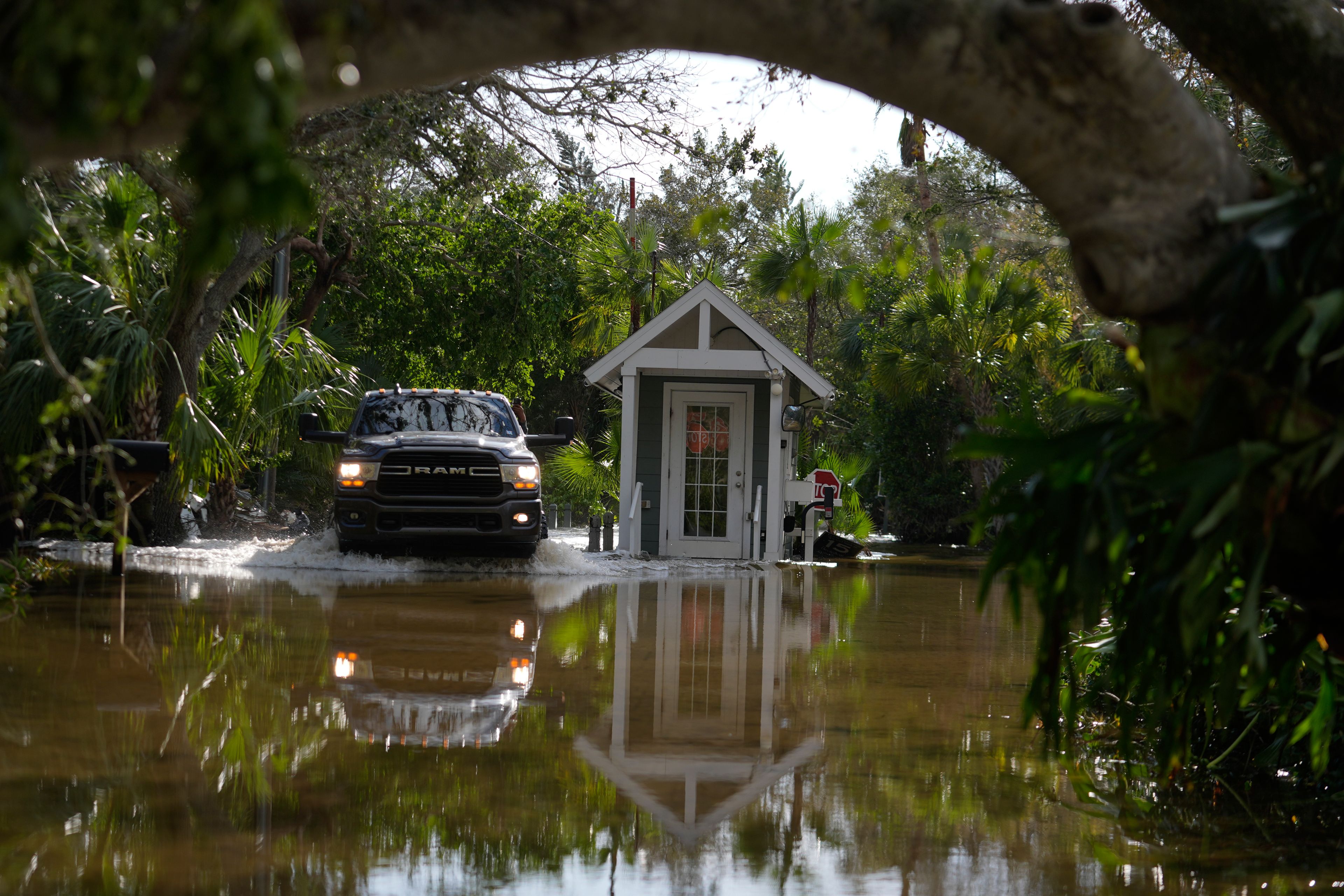 A pick up drives past a guard gate on a flooded street in Siesta Key, Fla., following the passage Hurricane Milton, Thursday, Oct. 10, 2024. (AP Photo/Rebecca Blackwell)