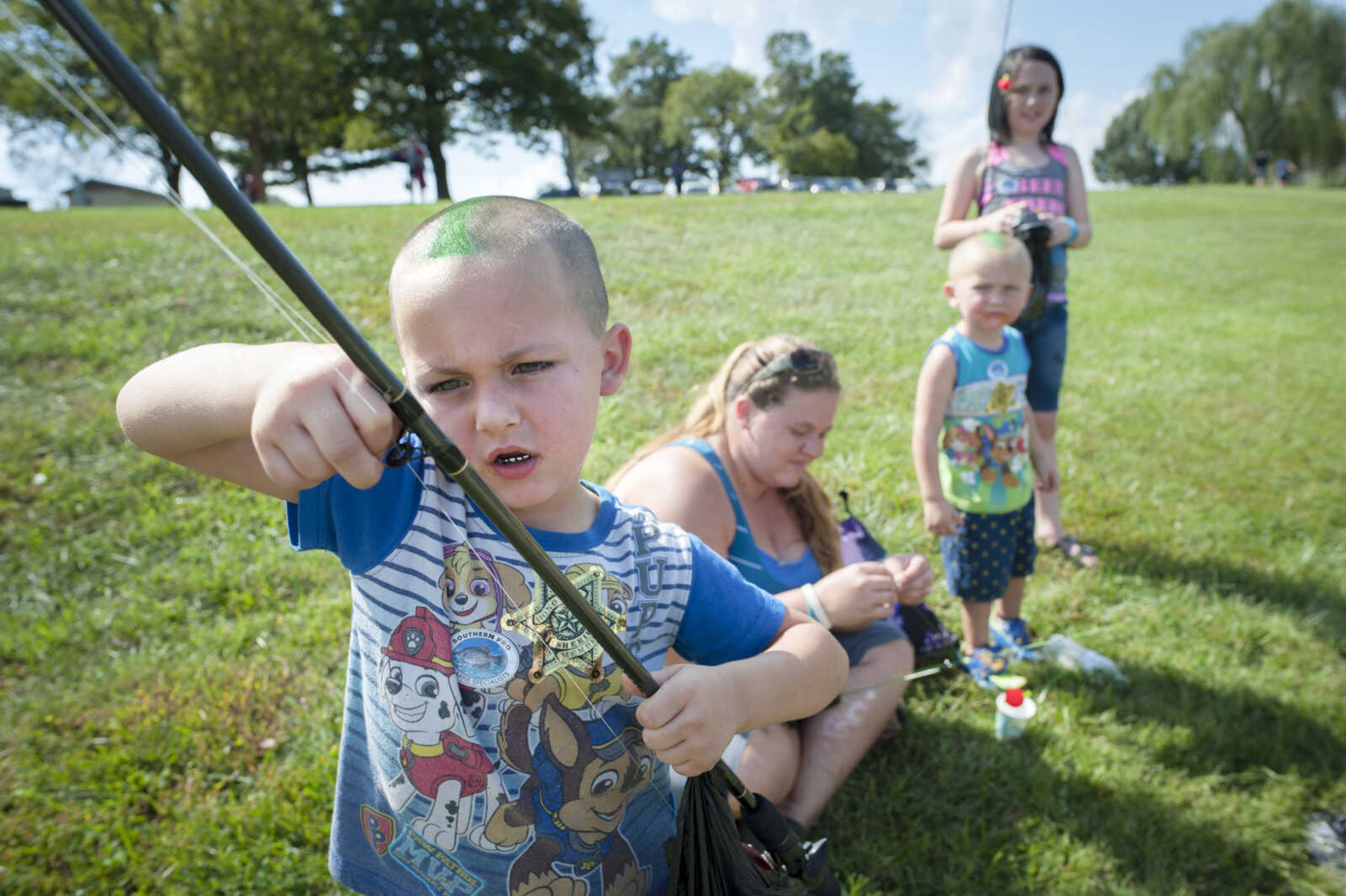 From left, Danny Shy, 4, attempts to free his hook from a guide on his pole as his mother, Kristin Shy, baits hooks for Bently Shy, 3, and Emalee Shy, 11, while fishing Sept. 29, 2019, at Cape County Park North.