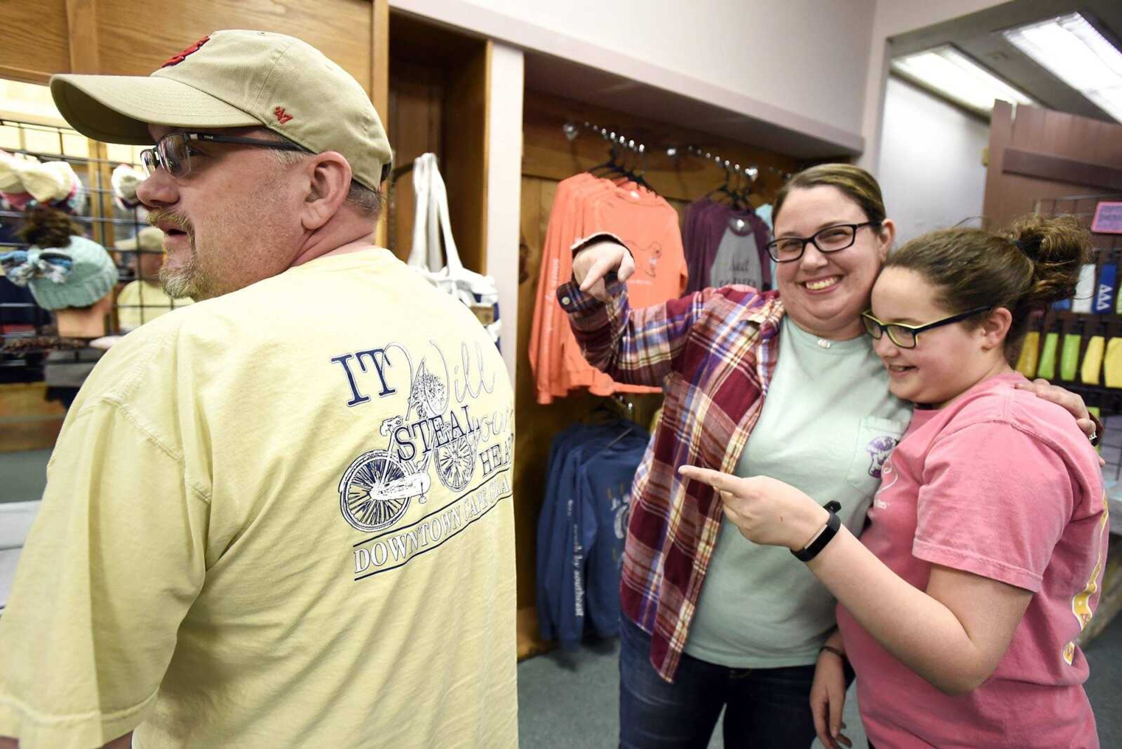 Kelli Seabaugh and her daughter Maddie point to the back of Steve Rector's shirt inside their downtown Cape Girardeau shop, Threadz.