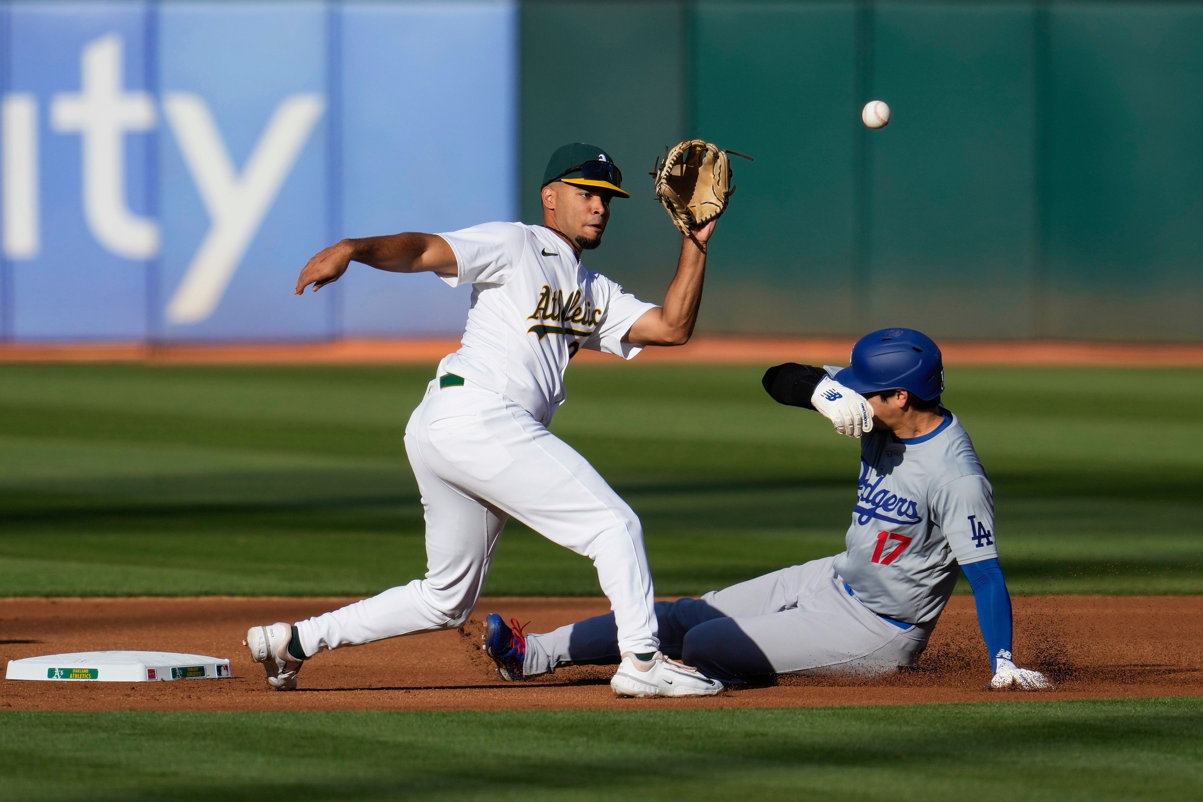 Oakland Athletics second baseman Darell Hernaiz, left, catches a throw from catcher Shea Langeliers as Los Angeles Dodgers' Shohei Ohtani (17) steals second during the first inning of a baseball game Saturday, Aug. 3, 2024, in Oakland, Calif. (AP Photo/Godofredo A. Vásquez)