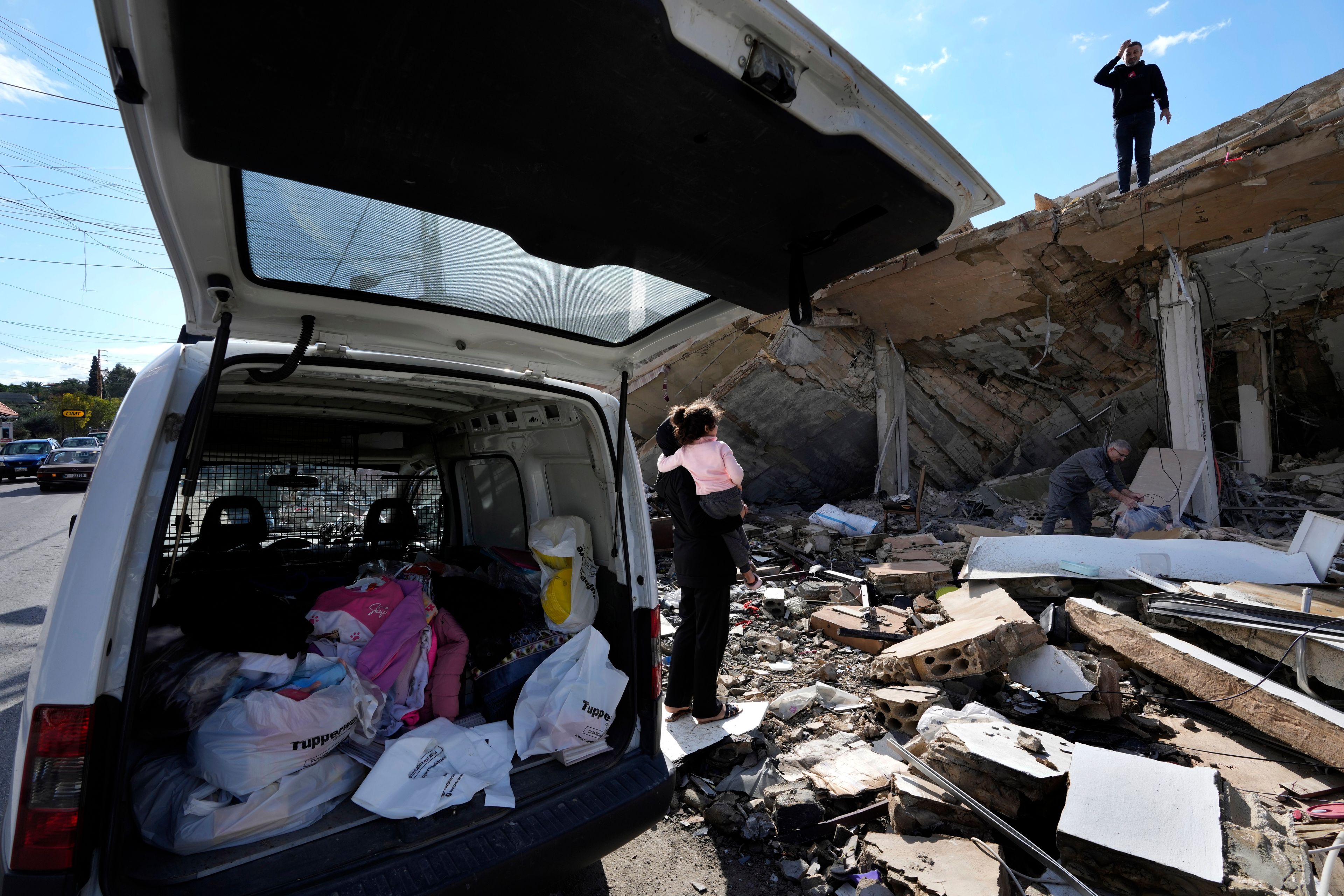 Safaa Haidous, carries her daughter Yara, 4, as she speaks with her husband Rawad Srour, who is stands on the roof of their family destroyed house, as they collect the remains of their belongings after they returned to Hanouiyeh village, southern Lebanon, Thursday, Nov. 28, 2024 following a ceasefire between Israel and Hezbollah that went into effect on Wednesday.(AP Photo/Hussein Malla)