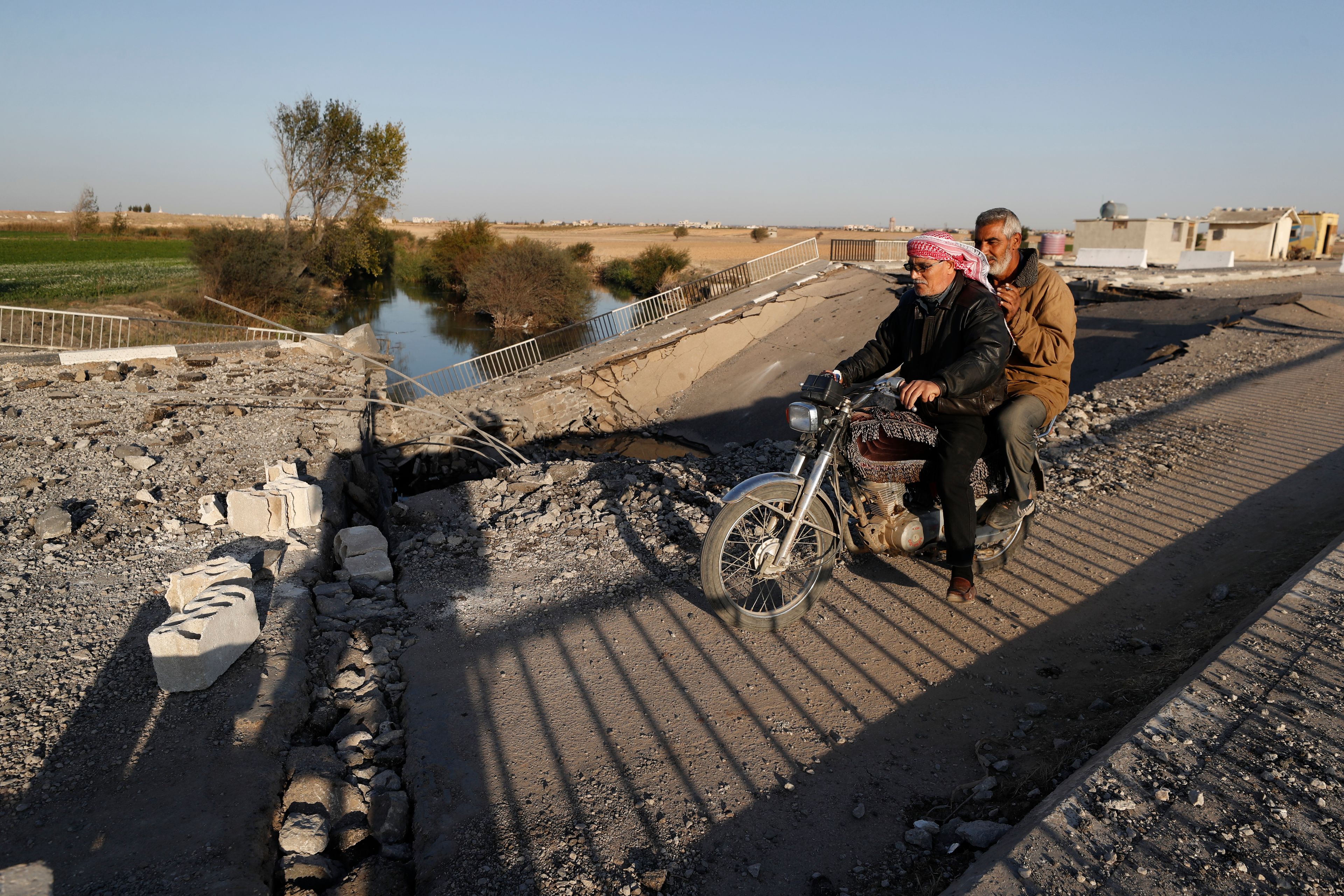 Syrian citizens ride a motorcycle as they cross a bridge that links to Lebanon which was destroyed on Oct. 24 by an Israeli airstrike, in Qusair, Syria, Sunday, Oct. 27, 2024. (AP Photo/Omar Sanadiki)