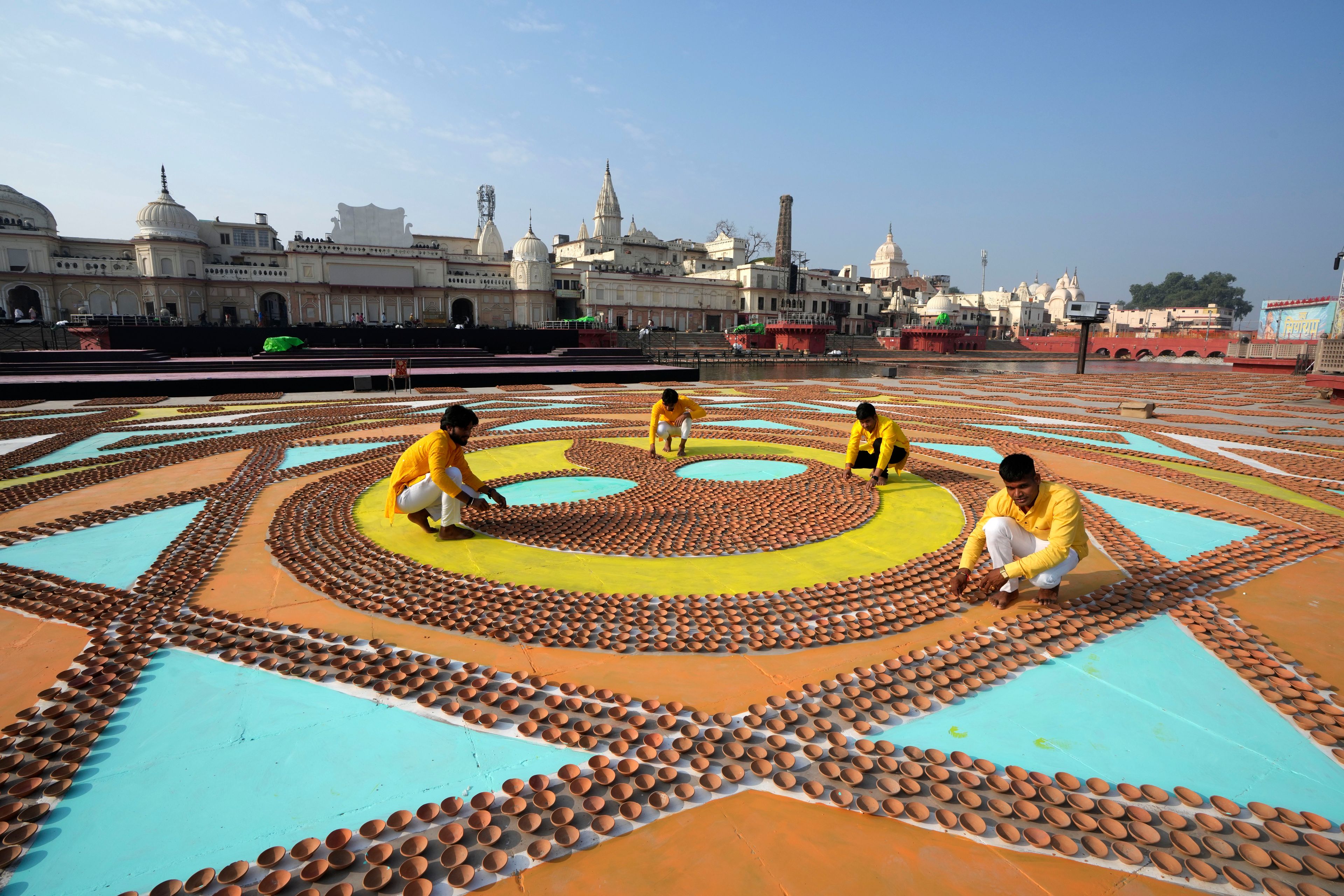 Volunteers place earthen lamps in geometric patterns on the banks of the Saryu river before Deepotsav celebrations, an event organized by the Uttar Pradesh state government on the eve of Diwali, in Ayodhya, India, Tuesday, Oct. 29, 2024. (AP Photo/Rajesh Kumar Singh)