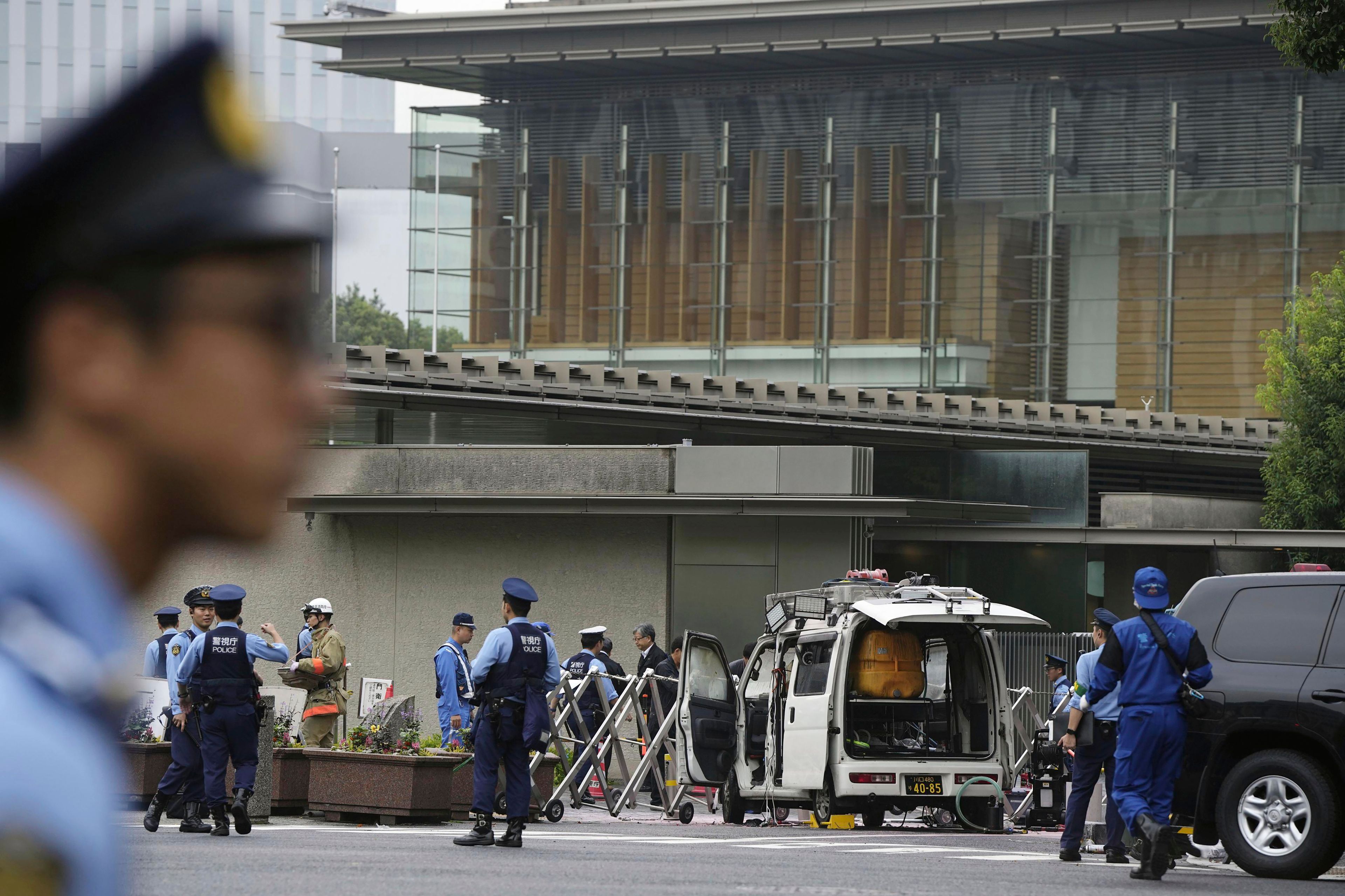 Police officers work near a vehicle, center, which was stuck against a barricade near the prime minister's office, background, in Tokyo Saturday, Oct. 19, 2024. (Kyodo News via AP)