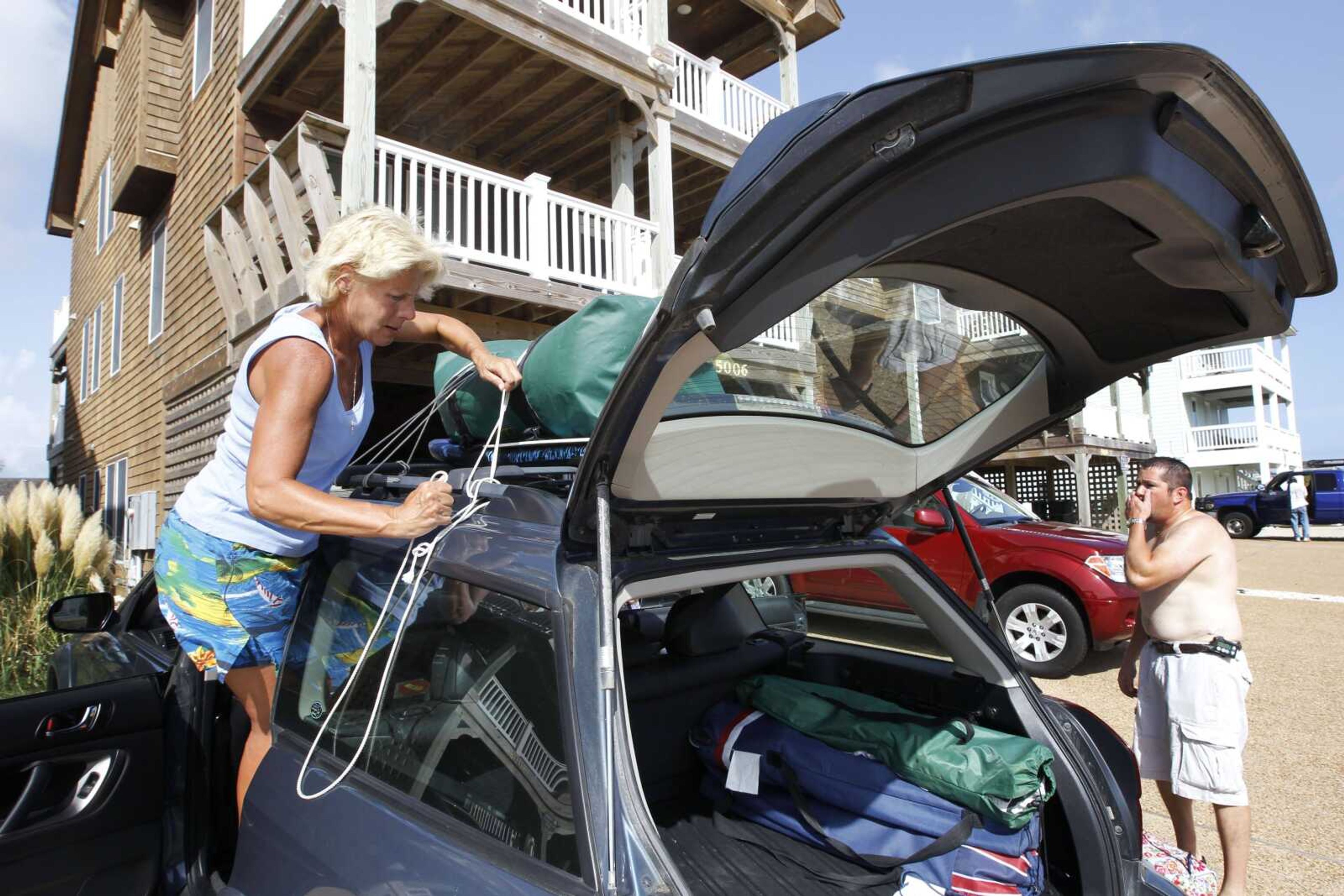 Heeding a mandatory visitor evacuation, Shawn Wyn of Cleona, Pa., right, and his family pack up Thursday as they leave their rented beach house in Nags Head, N.C. A hurricane watch was issued early Thursday for much of the North Carolina coast. Officials along the East Coast are calculating what they need to do if Irene becomes the first major hurricane to strike the region in seven years. The woman on the left did not want to be identified. (Charles Dharapak ~ Associated Press)