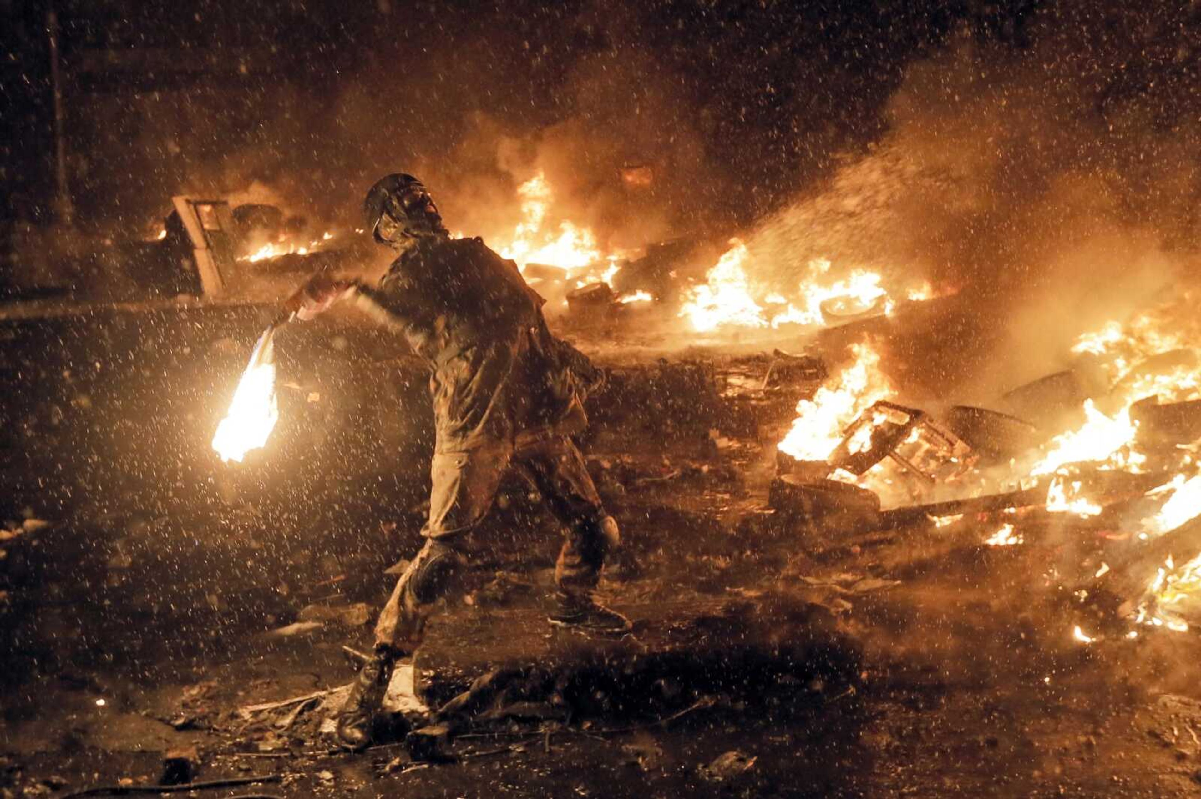 A protester throws a Molotov cocktail during clashes with police Jan. 22, 2014, in central Kiev, Ukraine. Tuesday, Ukraine marks the 10th anniversary of the uprising that eventually led to the ouster of the country's Moscow-friendly president.