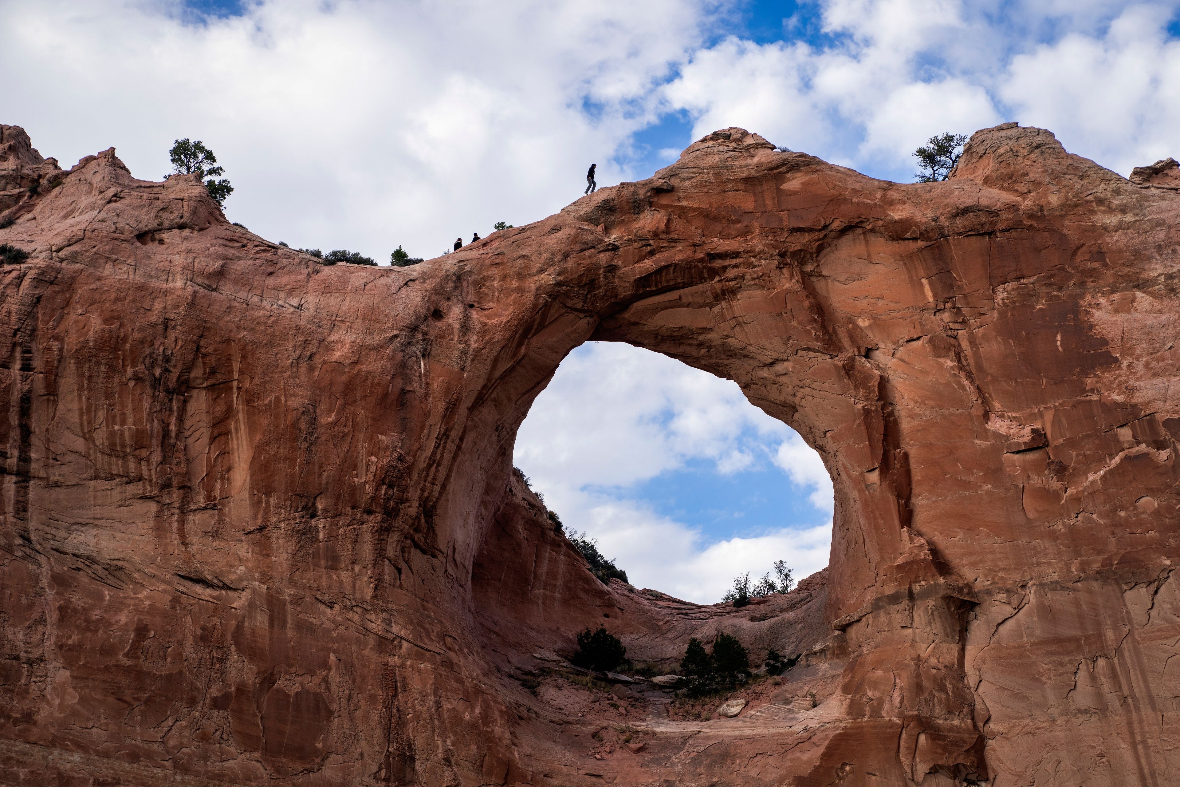 A man walks on the top of the red sandstone arch of Window Rock, Ariz., outside the Navajo Nation government headquarters, in Window Rock, Ariz., Thursday, Oct. 10, 2024. (AP Photo/Rodrigo Abd)