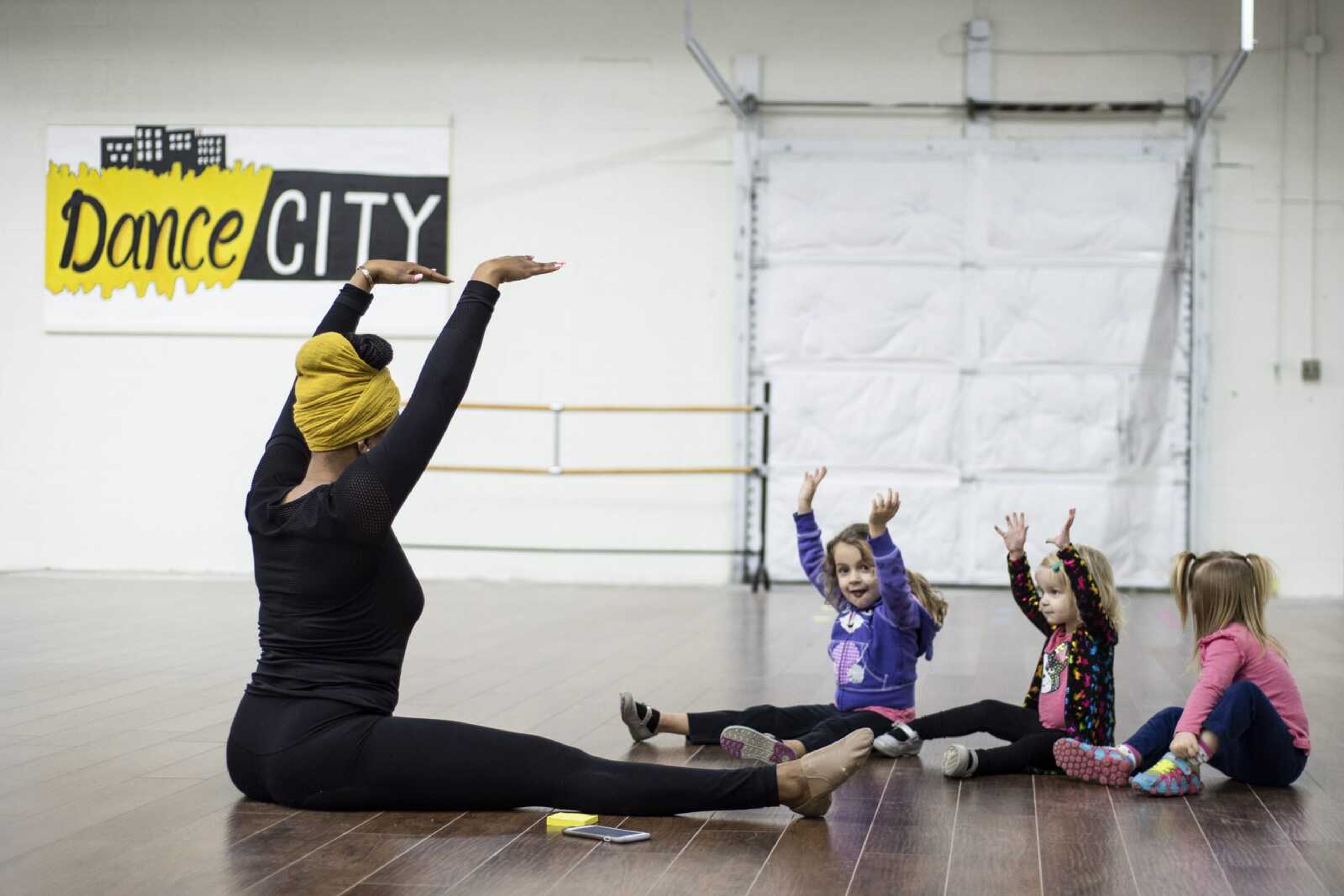 Jecala Amos leads stretches with her Monday morning "baby hop" class students (from left) Nora Oslund, 4, Greta Oslund, 2, and Josie Oslund, 2, at Dance City in Cape Girardeau.