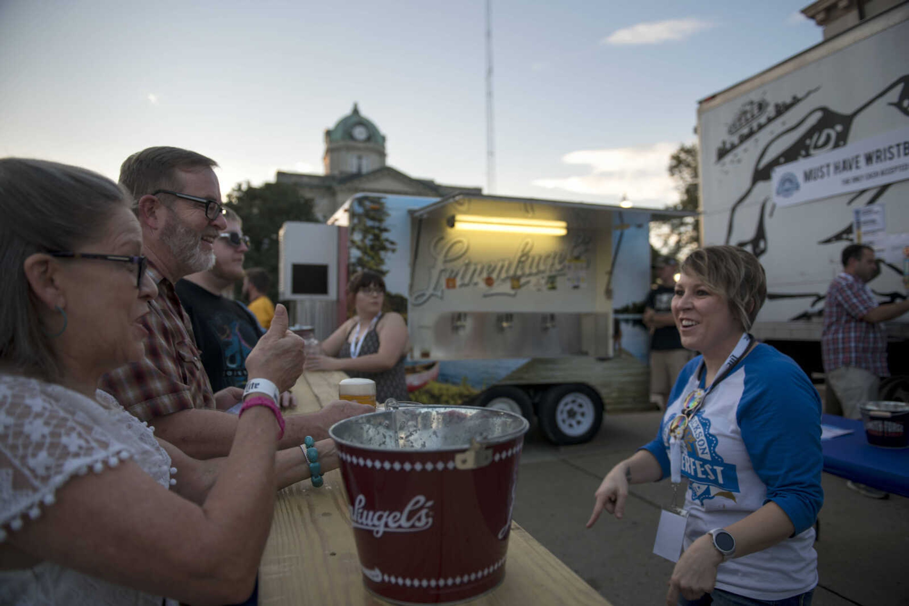 Serena Schooley, right, talks with patrons at a beer bar during Uptown Jackson Oktoberfest's opening night Friday, Oct. 5, 2018.