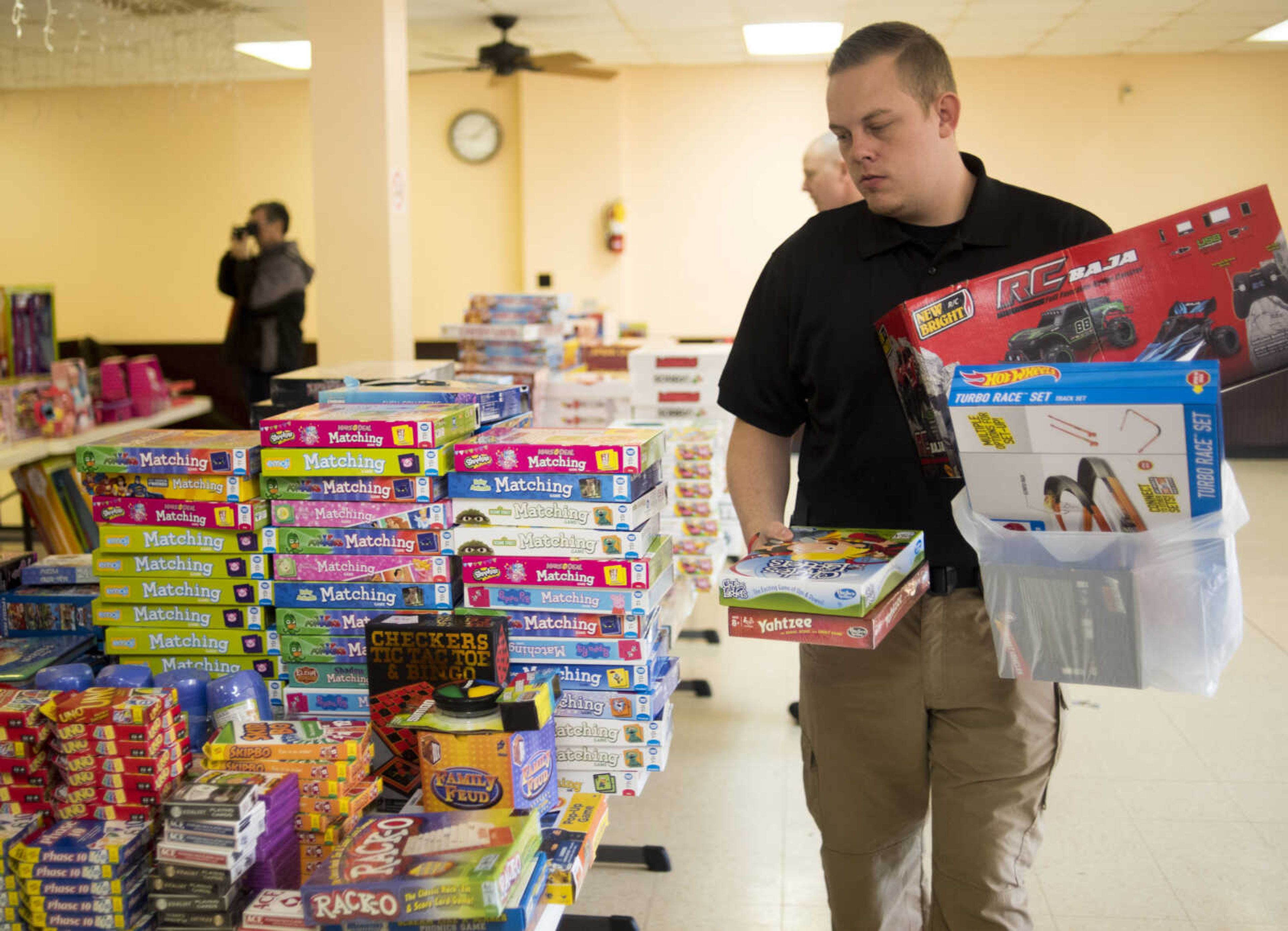 School resource officer Timothy Lester picks up an armful of toys and games to give to local families Friday, Dec. 15, 2017, at Elks Lodge #2652 in Jackson.