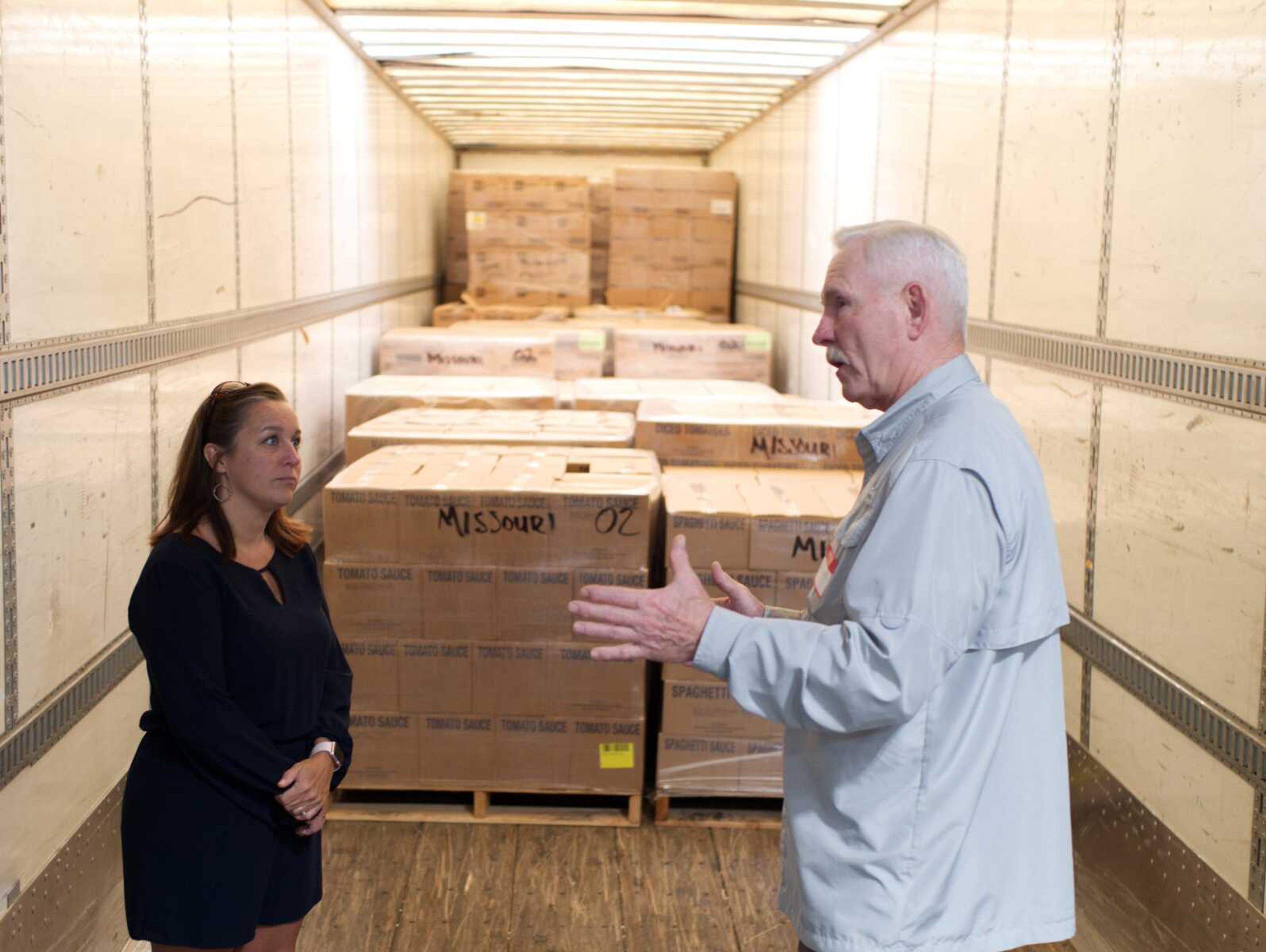 Tara Guzman, resource aquisition specialist for the Southeast Missouri Food Bank and Larry Beard of the Church of Jesus Christ of Latter-day Saints have a conversation in front of the food donated by the church.